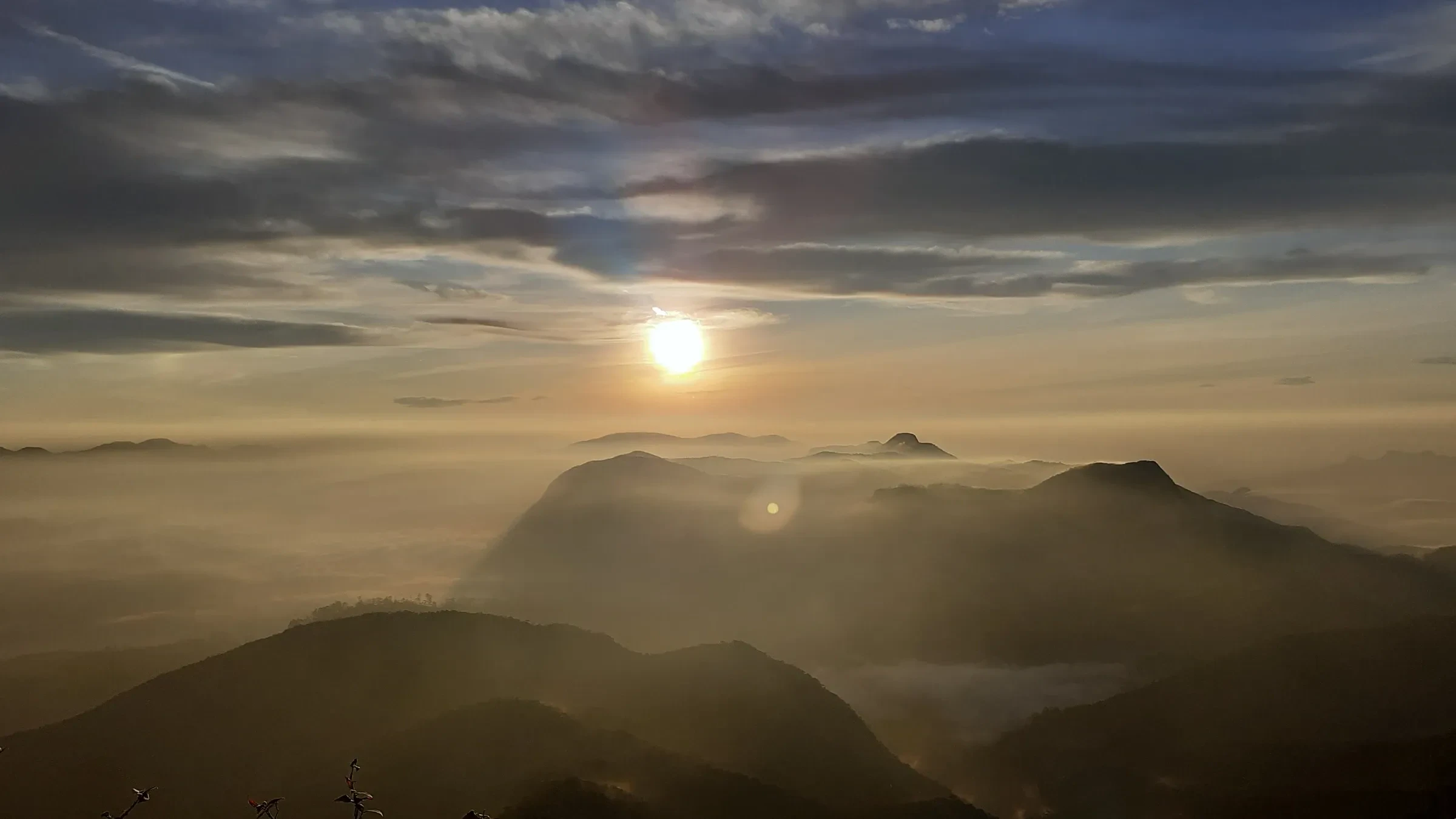 The sun rising over mist-filled hills from the summit of Sri Pada, Adam's Peak
