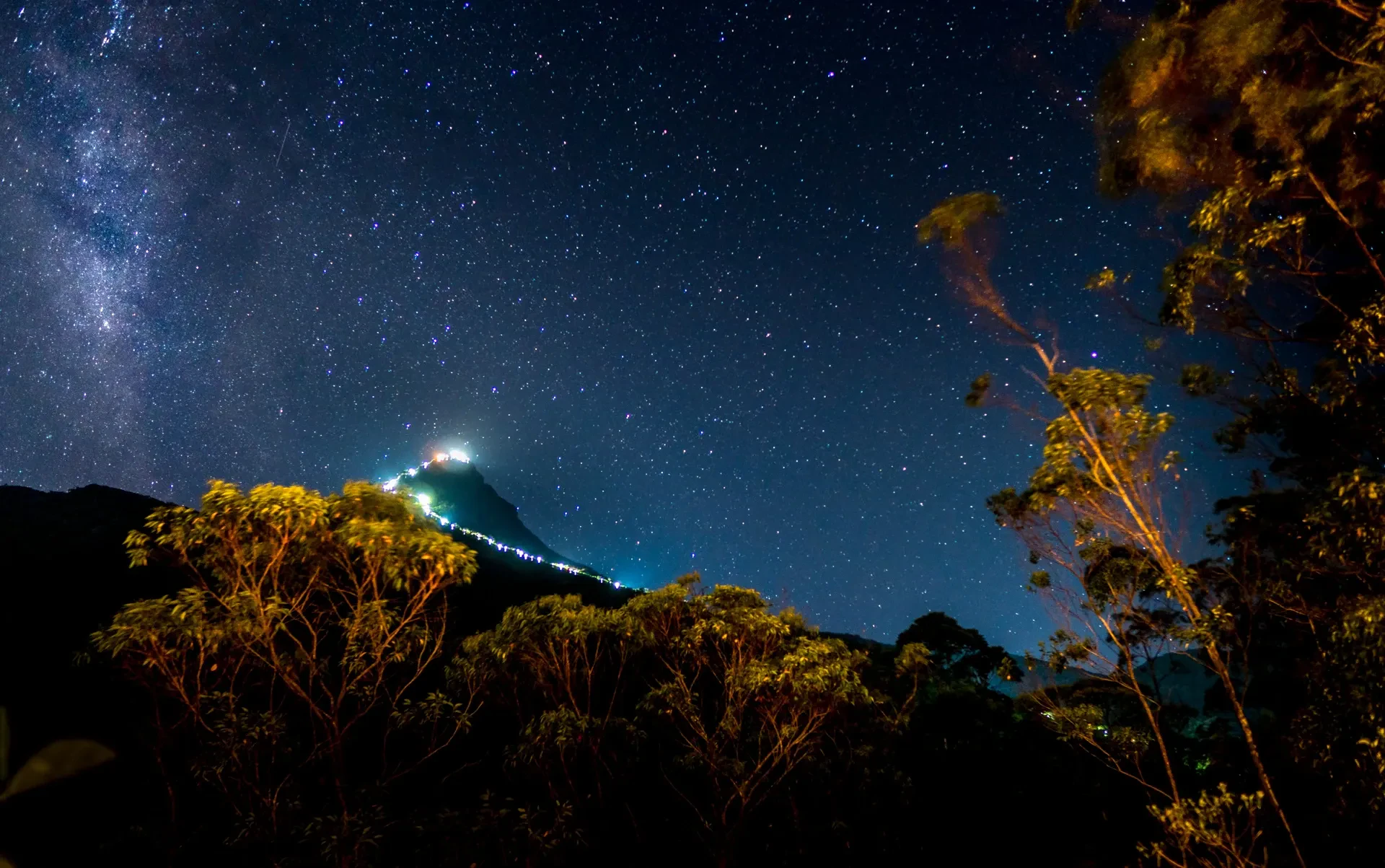 Sri Pada at night with the lights of the summit path glowing under a starry sky