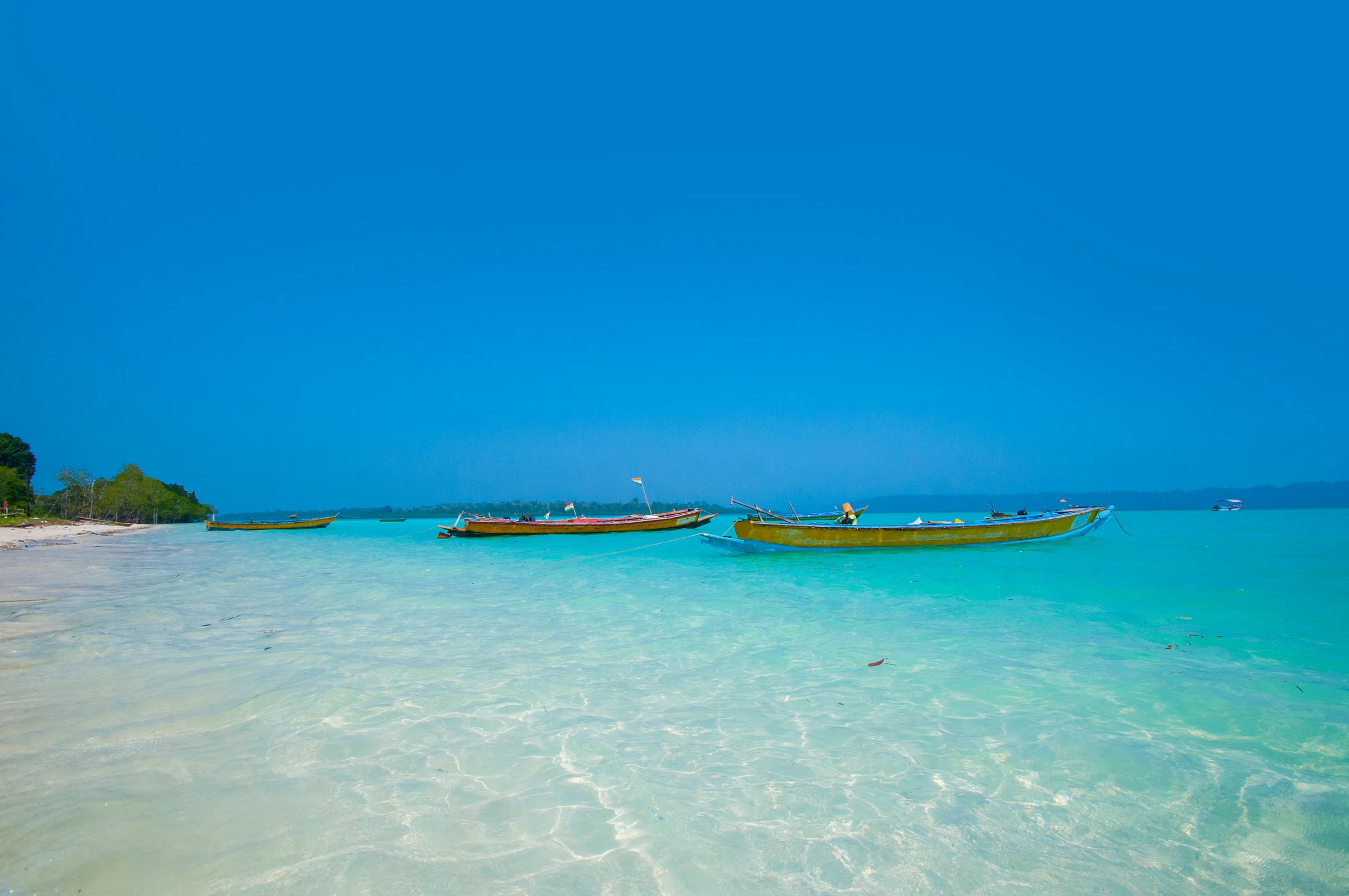 Wooden boats moored in clear turquoise water off the Andaman Islands