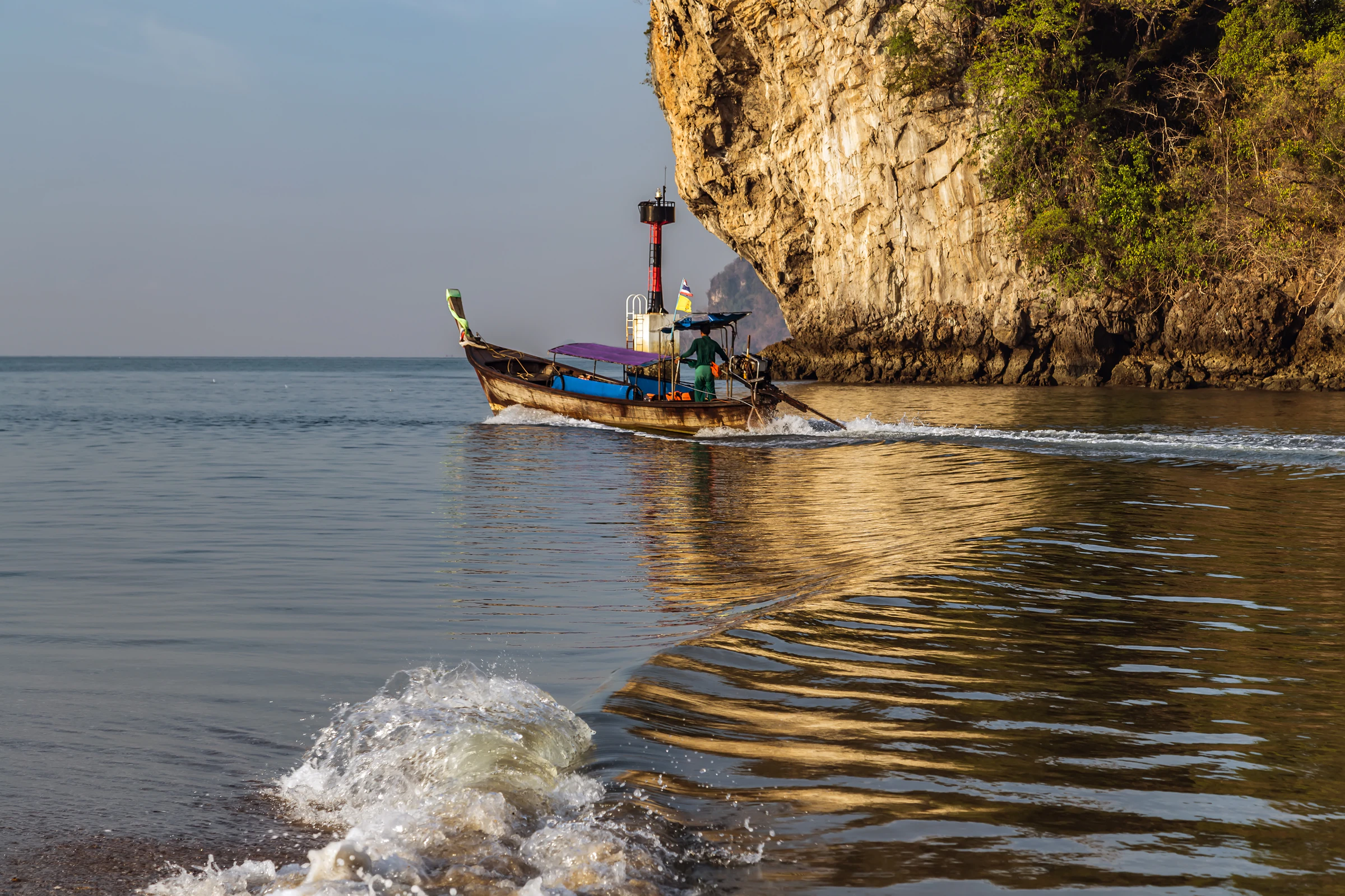 Longtail boats moored beneath limestone cliffs on Krabi's Andaman coast
