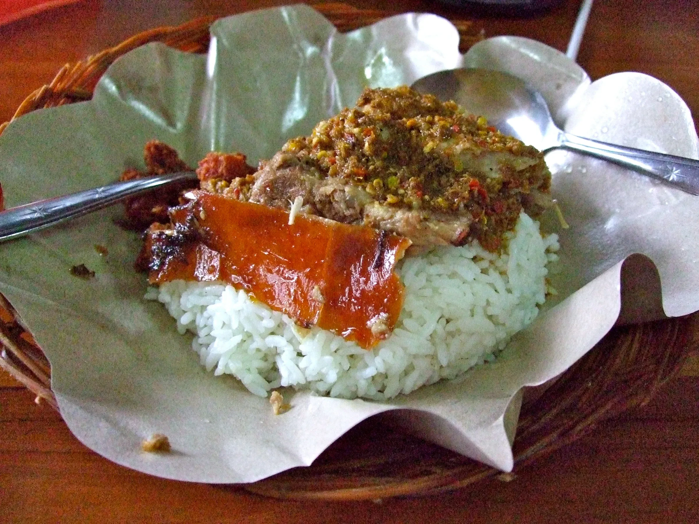 Babi guling with crackling skin served over rice on a banana leaf