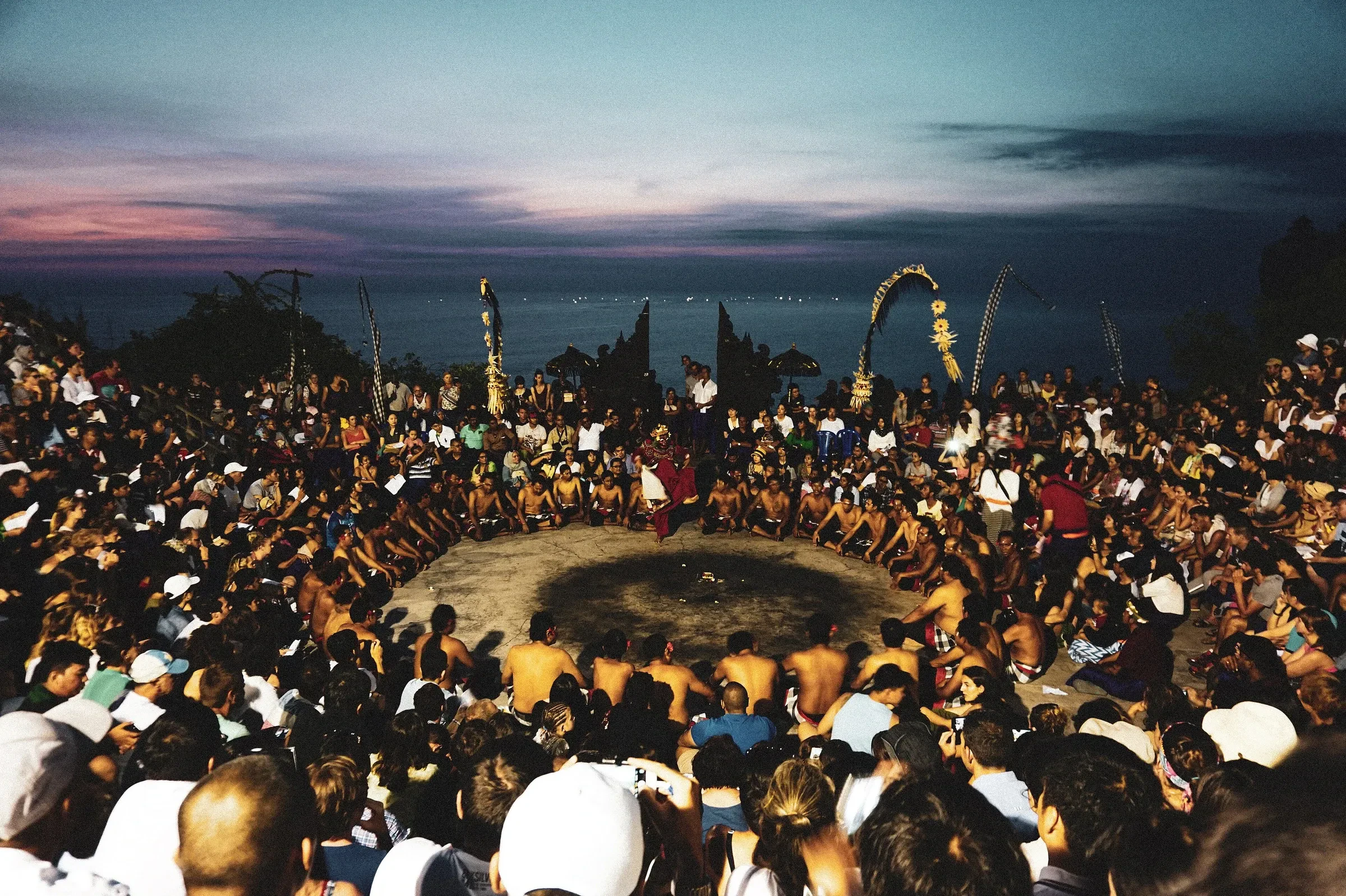 A packed crowd around the Kecak fire dance circle at dusk at Uluwatu