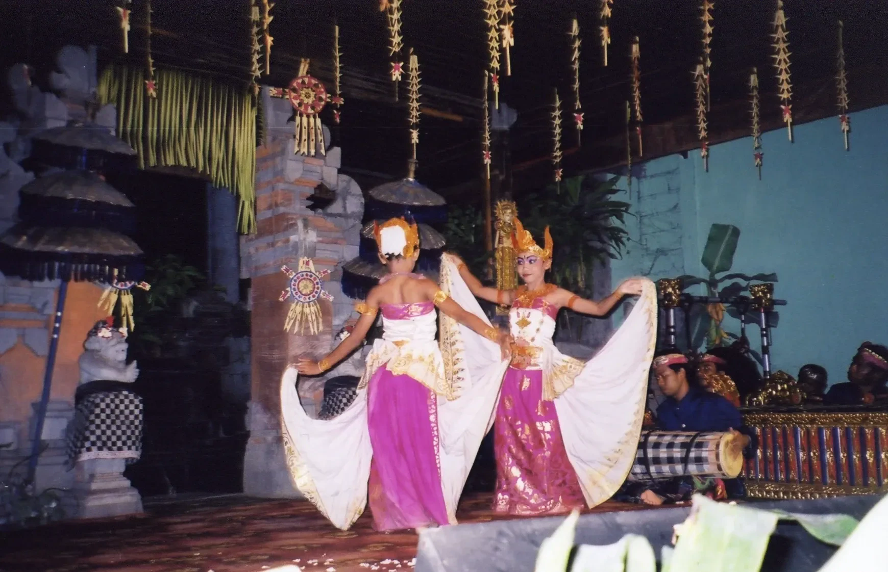 Two Legong dancers in pink and gold costumes performing on a stage in Ubud