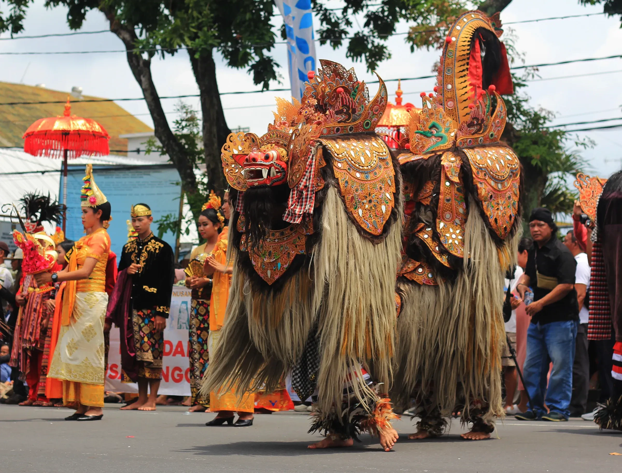 Barong figures and people in traditional dress in a street procession in Bali