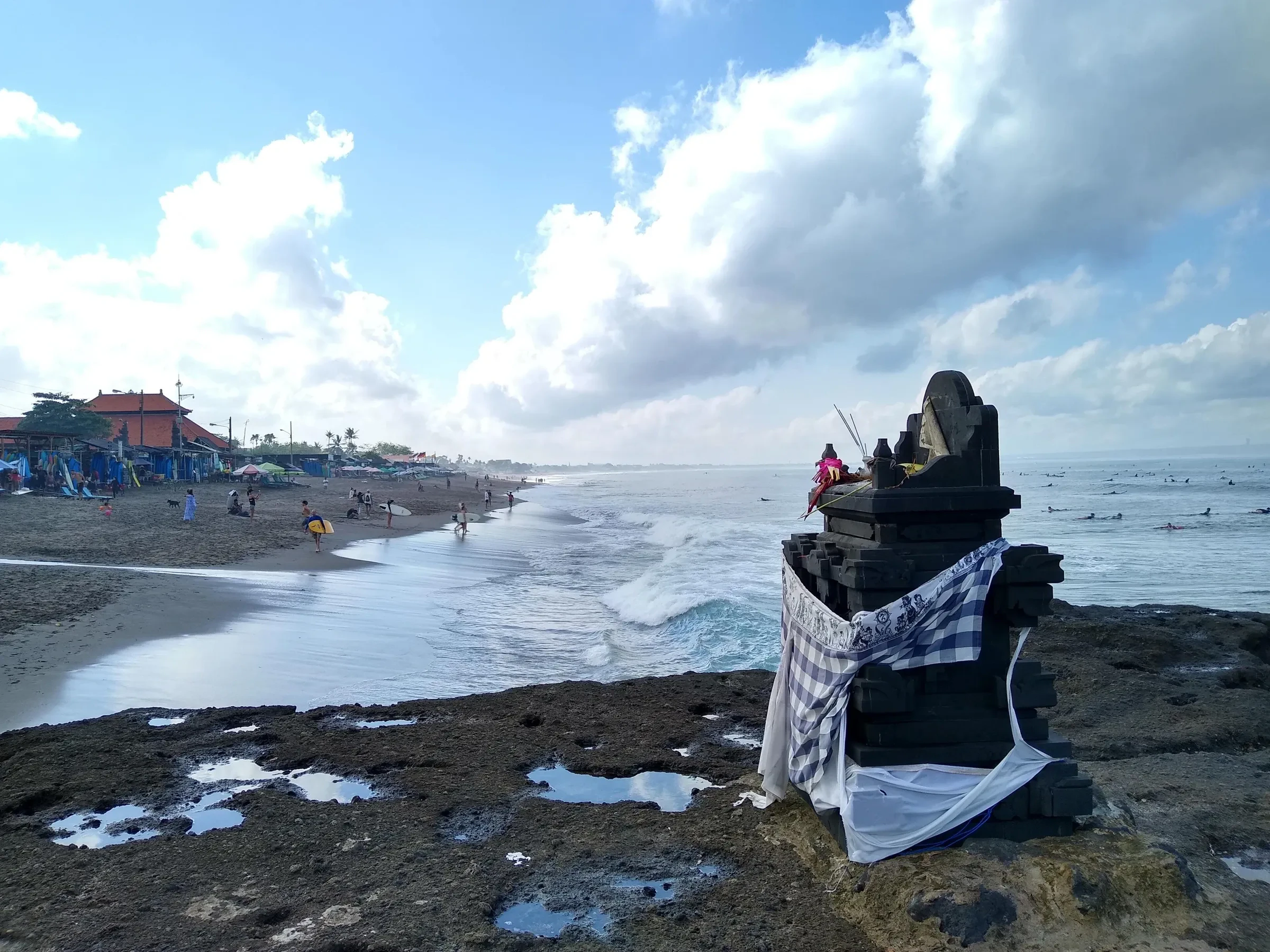 Black sand and a small shrine on the rocks at Canggu beach