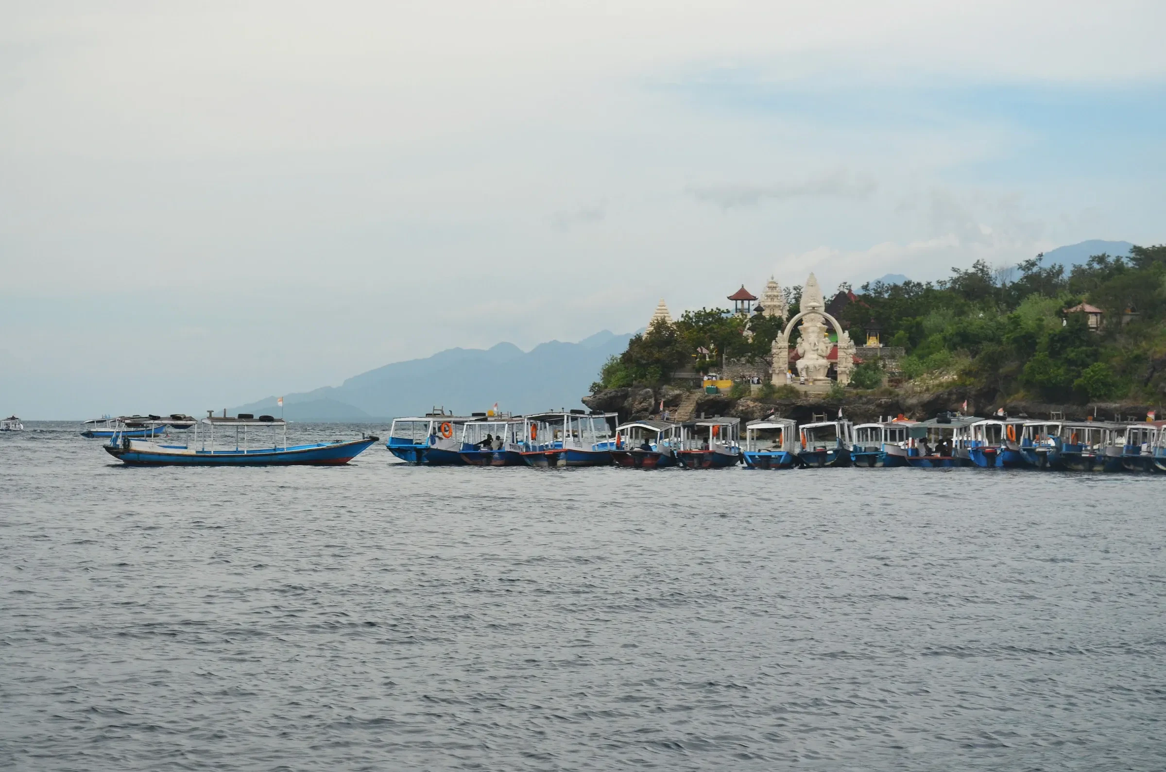Dive boats moored at Menjangan Island off Bali's northwest coast, with a temple on the hill behind