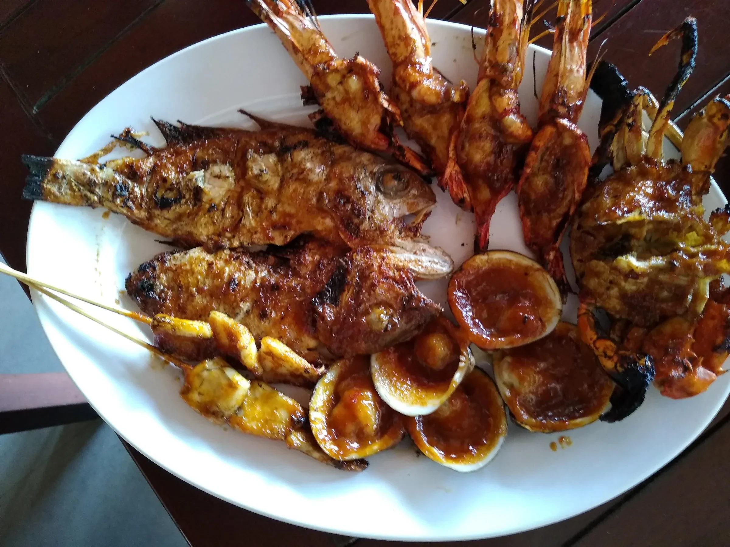 Grilled fish, prawns and clams on a plate at a beachfront restaurant in Jimbaran