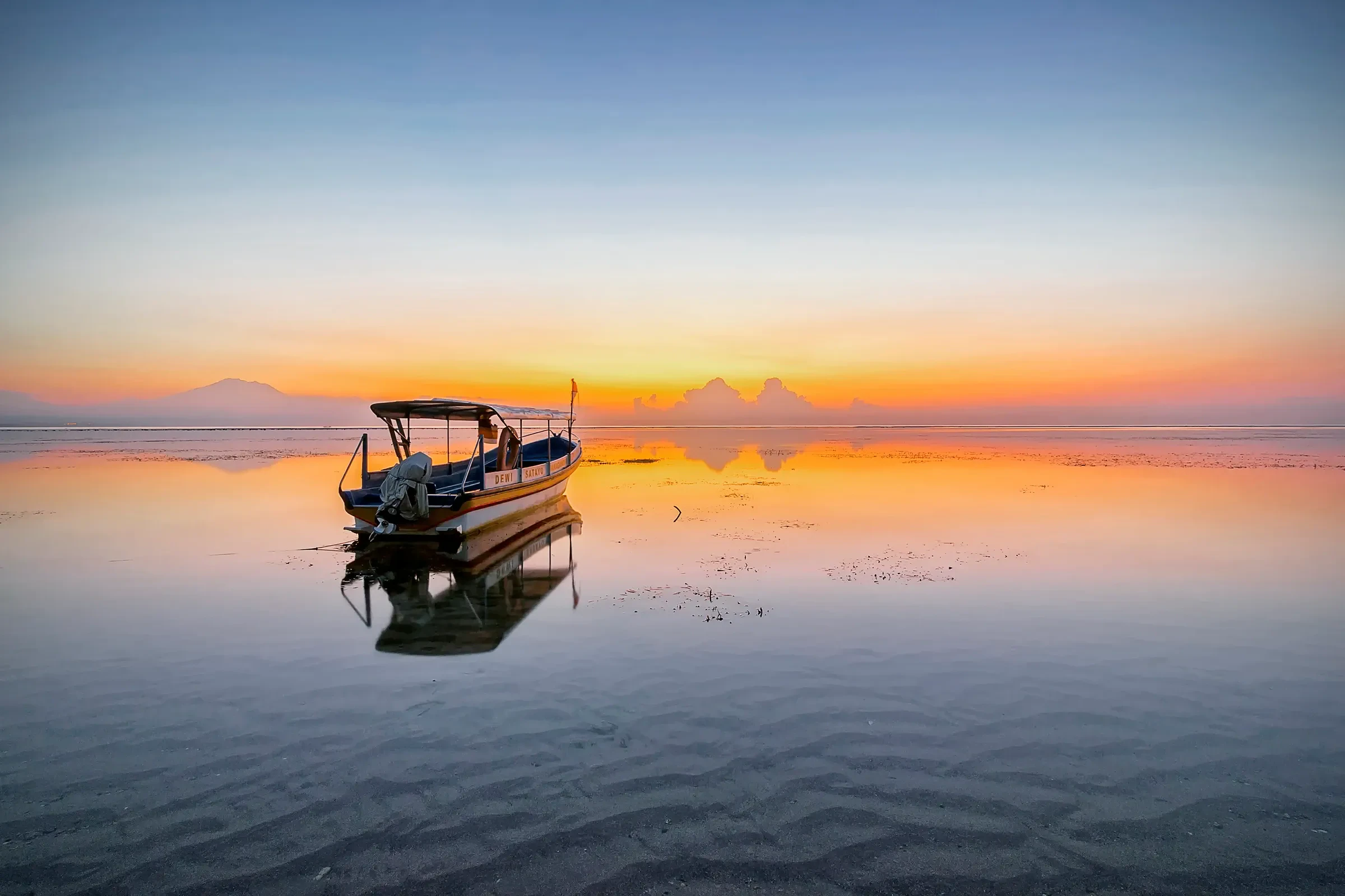 A small boat on calm water at sunrise off Sanur beach, Bali