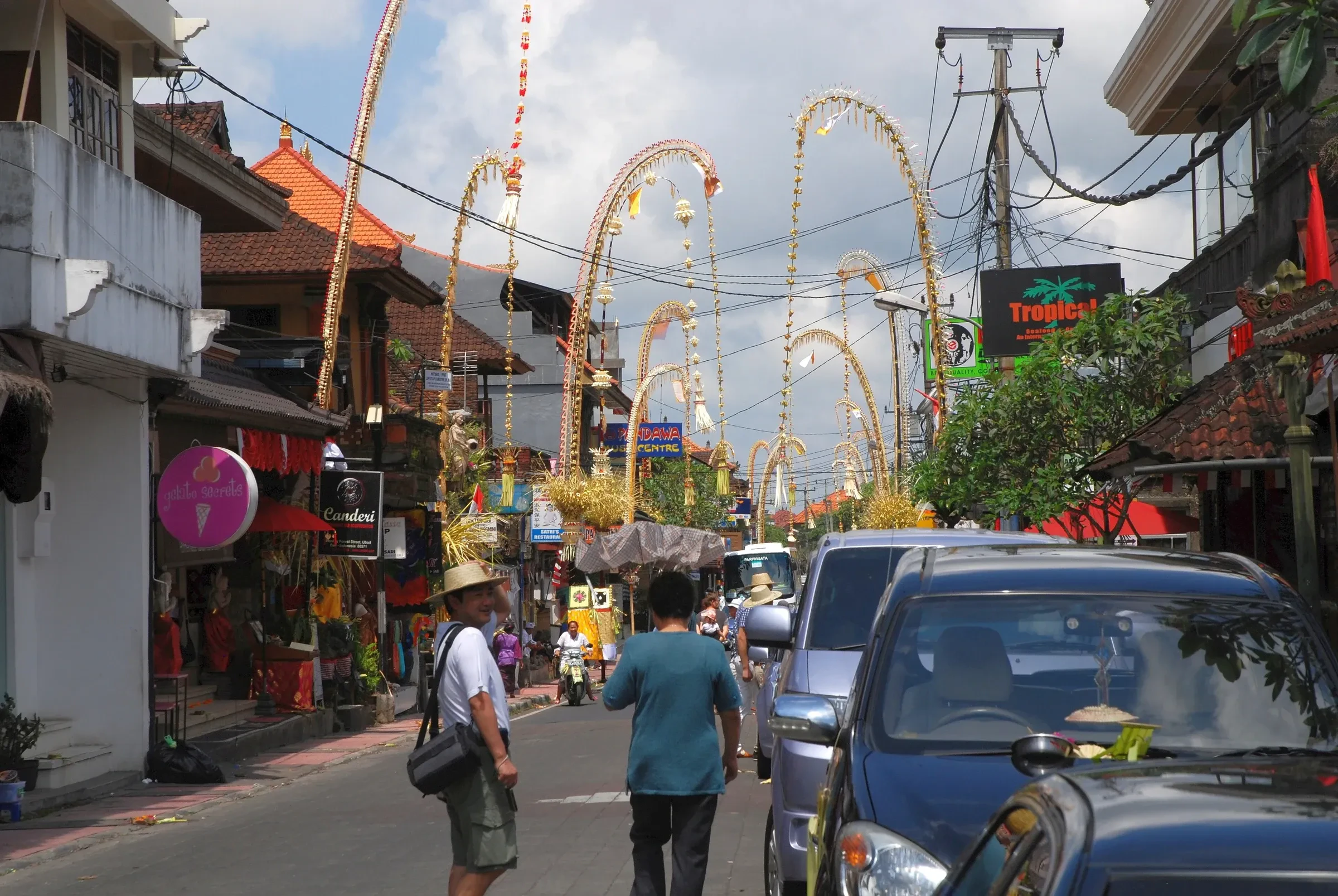 A Bali street lined with tall decorated penjor poles during Galungan in Ubud
