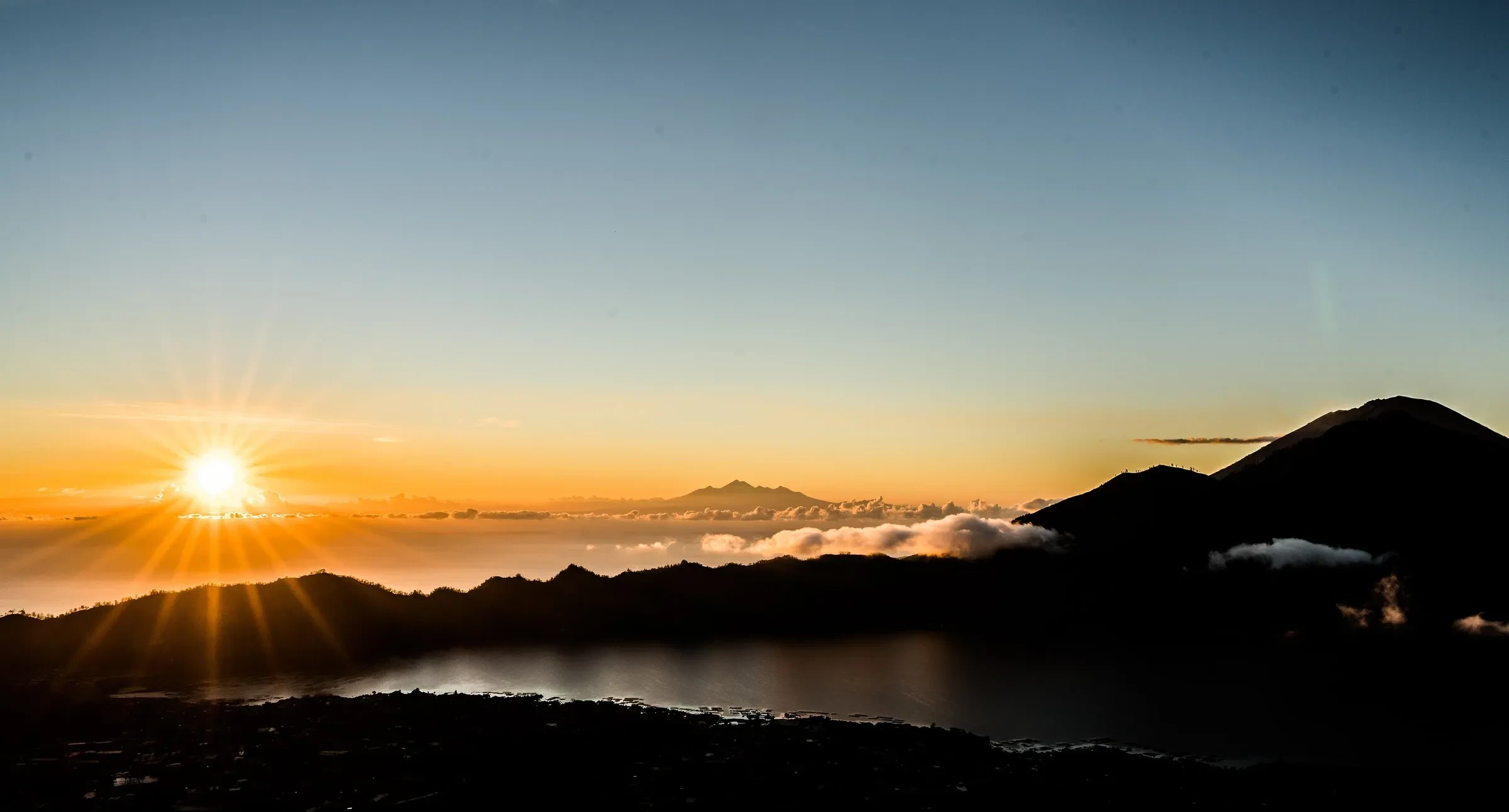 Sunrise over the crater of Mount Batur, with the lake and clouds below