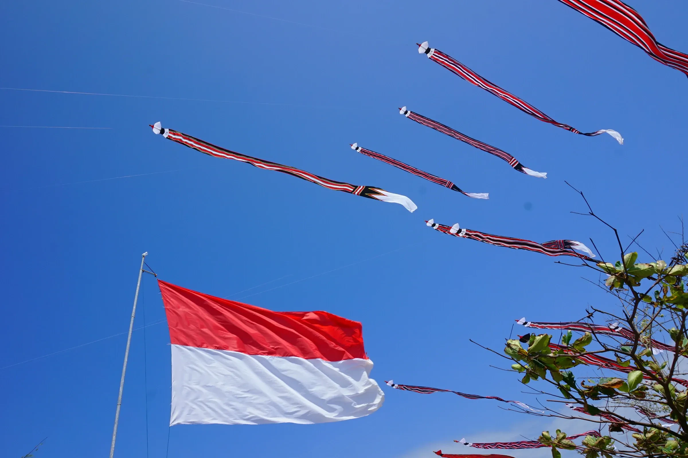 Giant traditional kites and an Indonesian flag against a blue sky at the International Bali Kite Festival, Mertasari Beach, Sanur