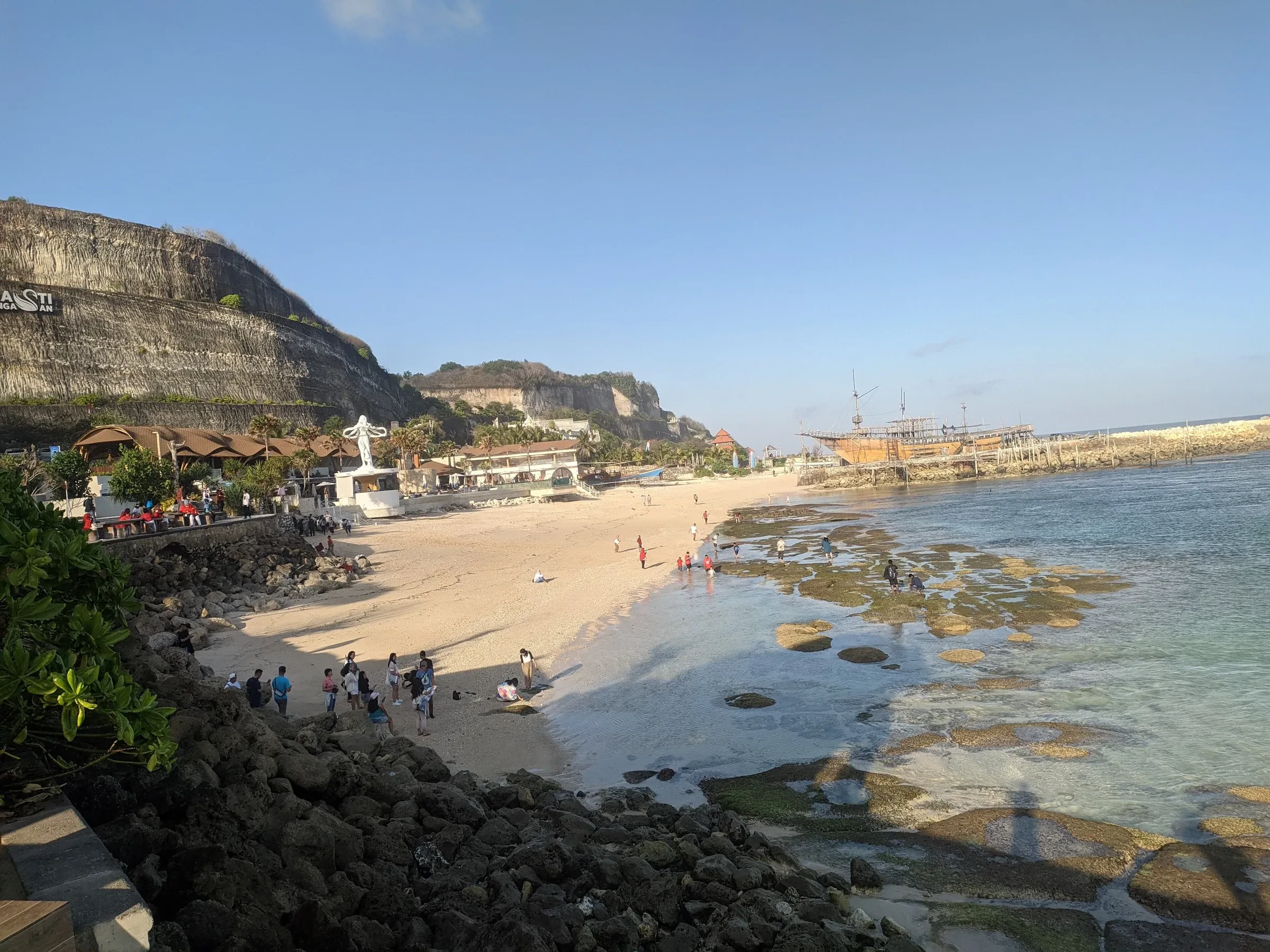 Melasti Beach's pale sand and shallow water below the limestone cliffs