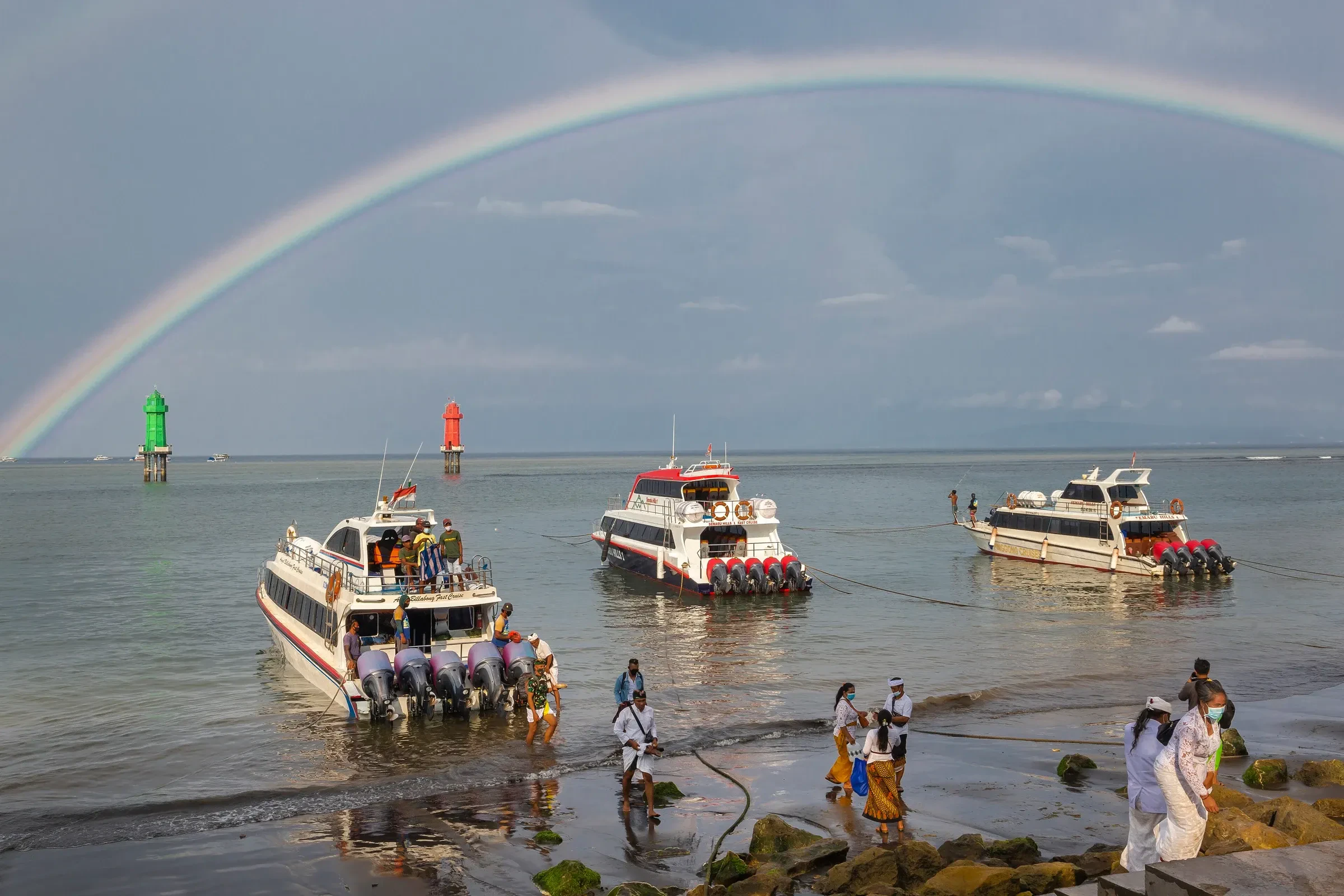 Fast boats waiting off Sanur beach under a rainbow, Bali