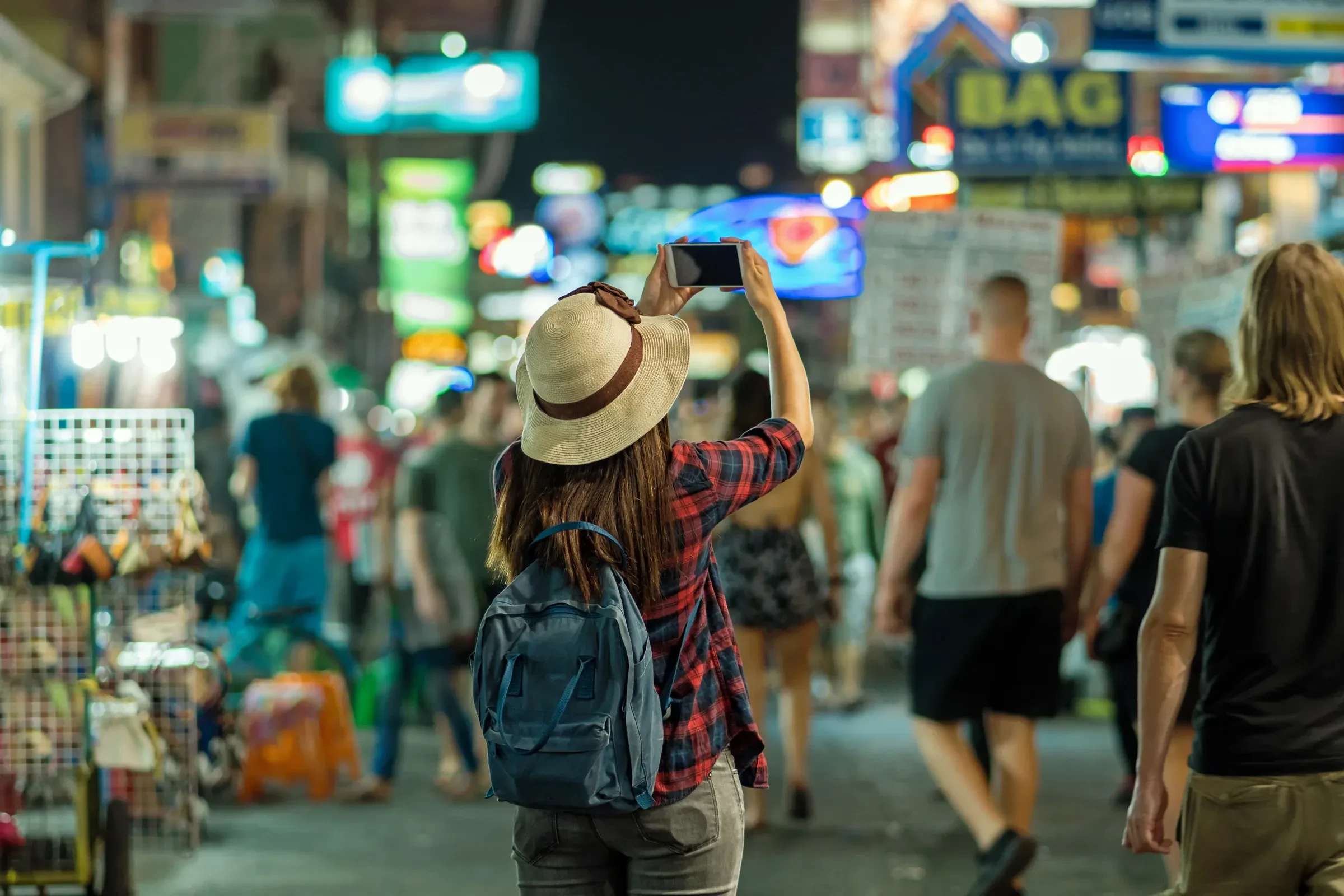 A traveller taking a photo of the neon signs on Khao San Road at night