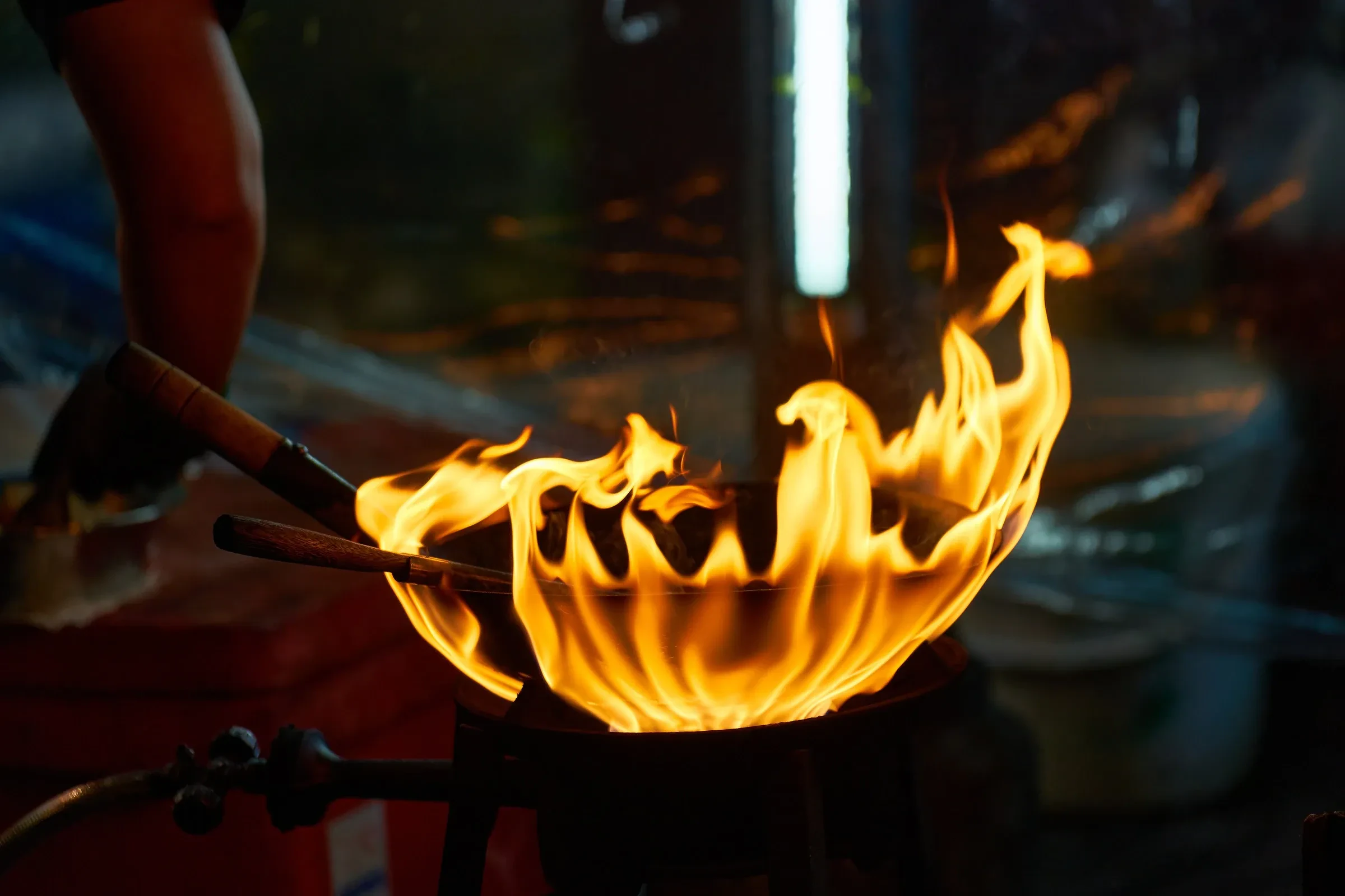 A cook's flaming wok at a street food stall in Bangkok's Chinatown
