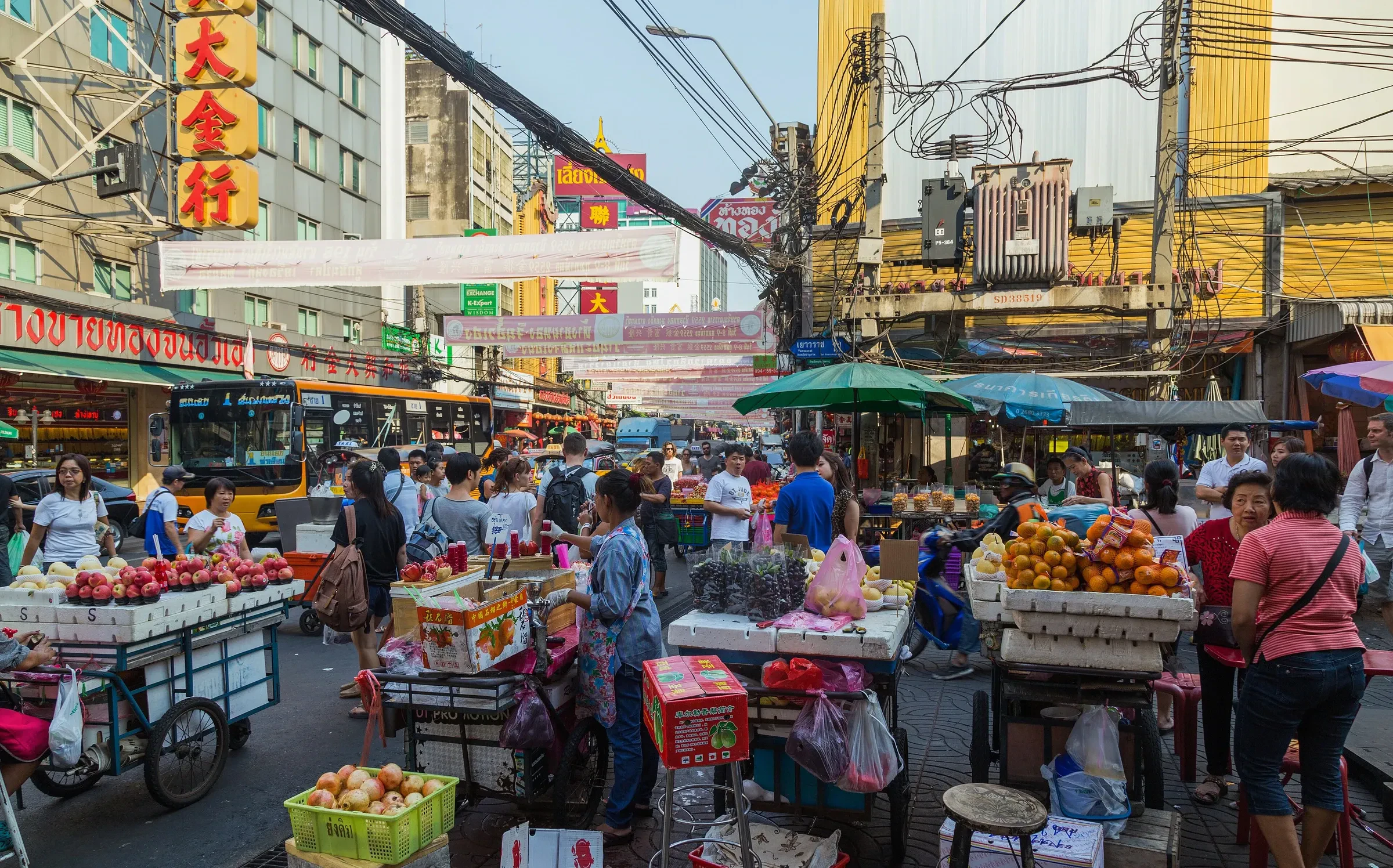 Fruit and snack carts and shoppers on Yaowarat Road in Bangkok's Chinatown