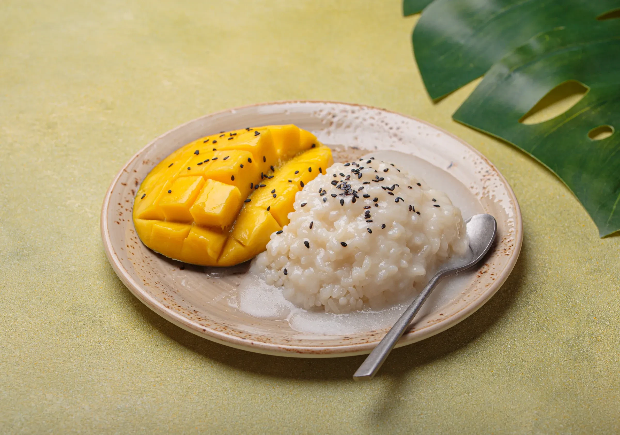 Ripe mango with sticky rice and black sesame seeds on a plate