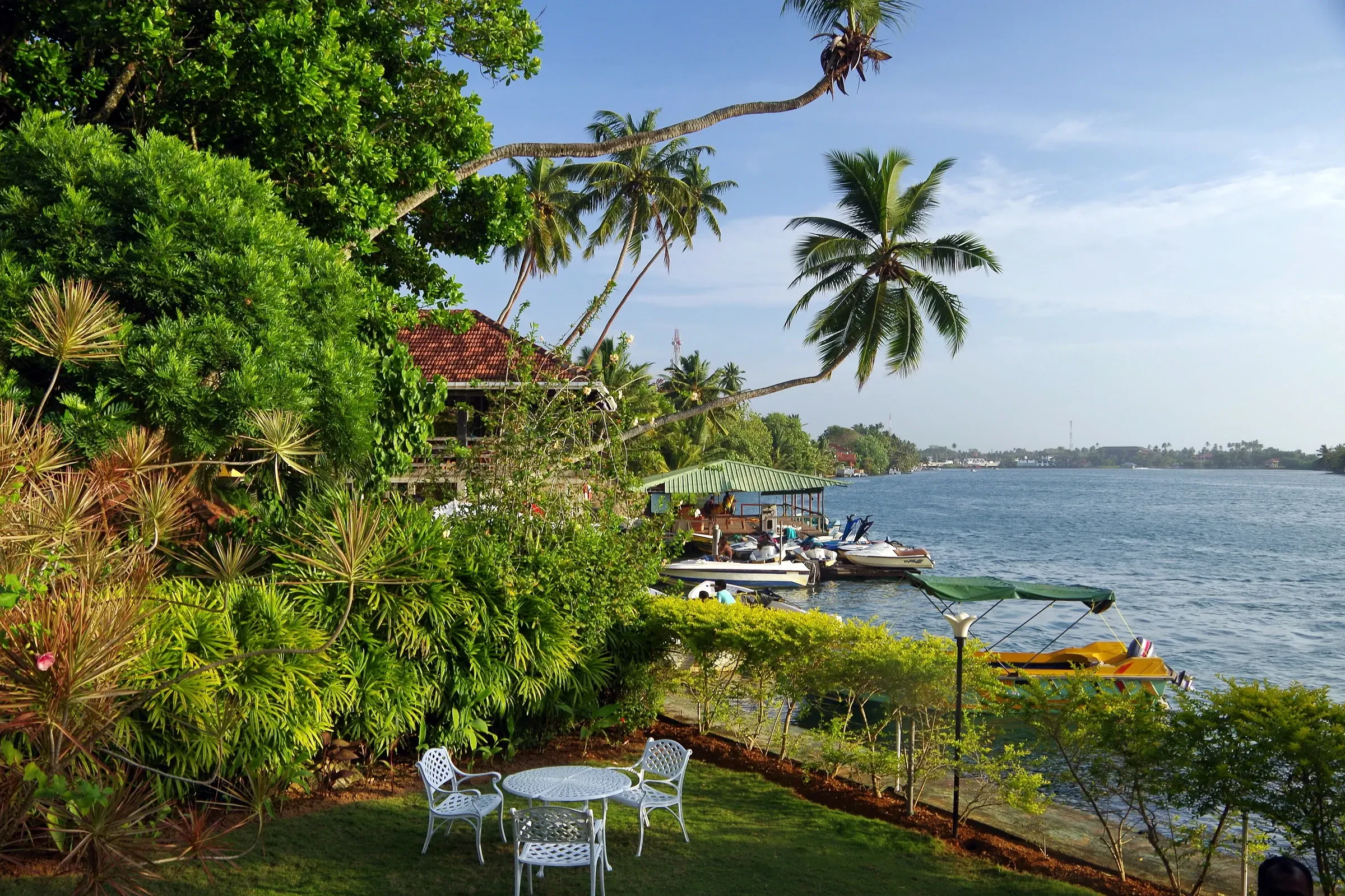 Boats moored beside waterfront gardens on the Bentota river at Aluthgama