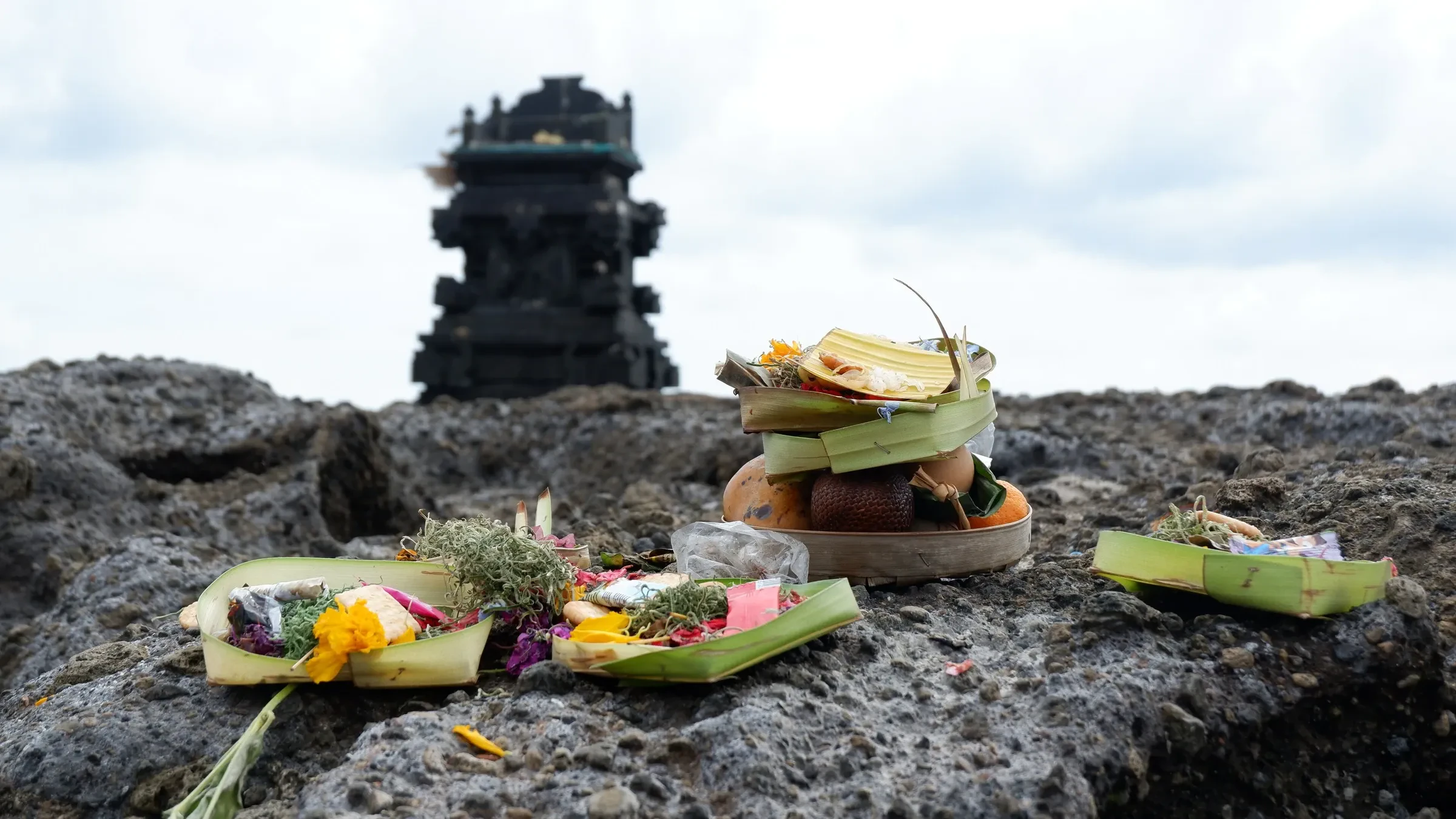 Offerings left on a rock at Canggu Beach, with a small shrine behind