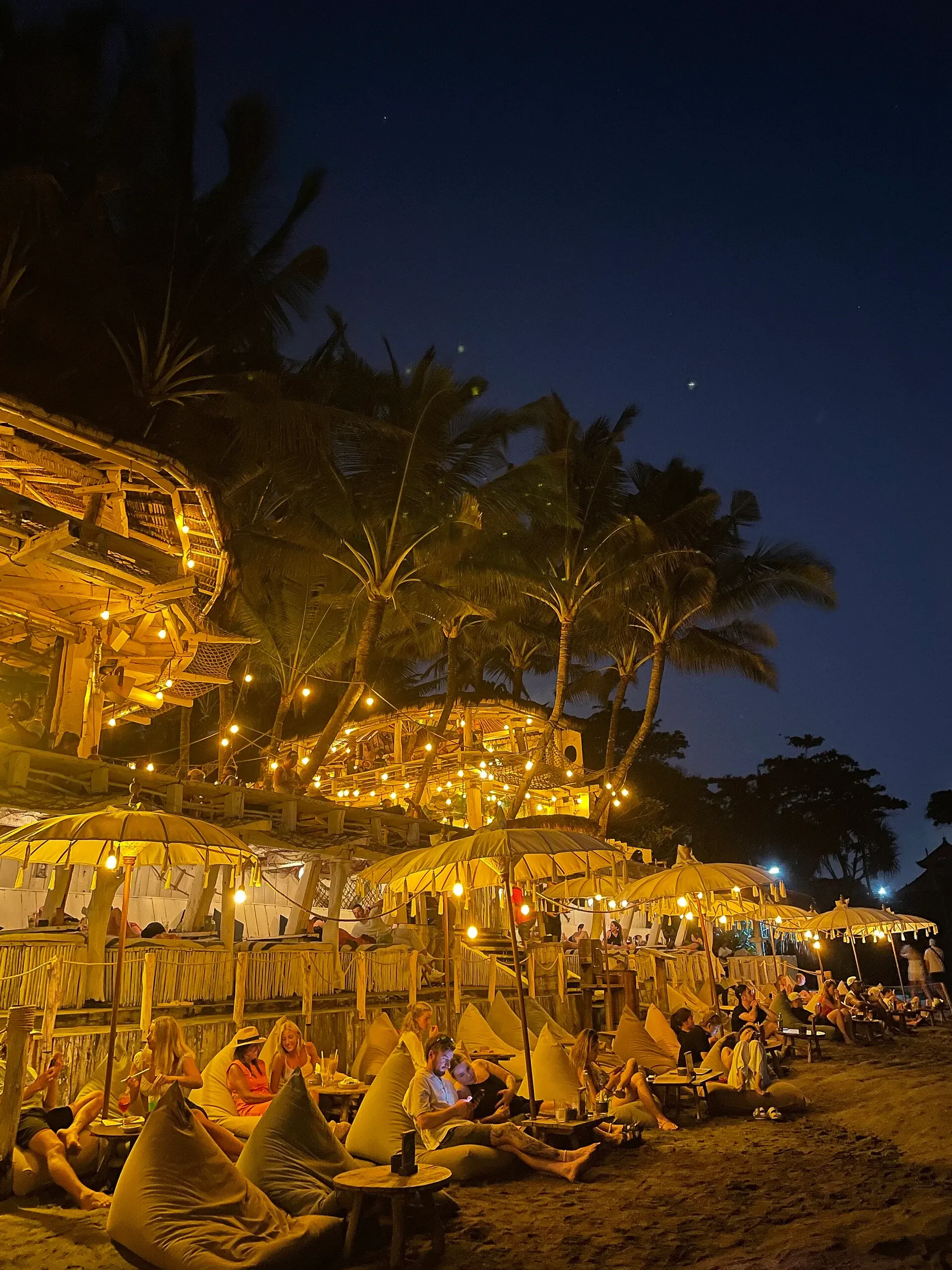 Beach club on Echo Beach at night, with string lights, bean bags and people relaxing on the sand