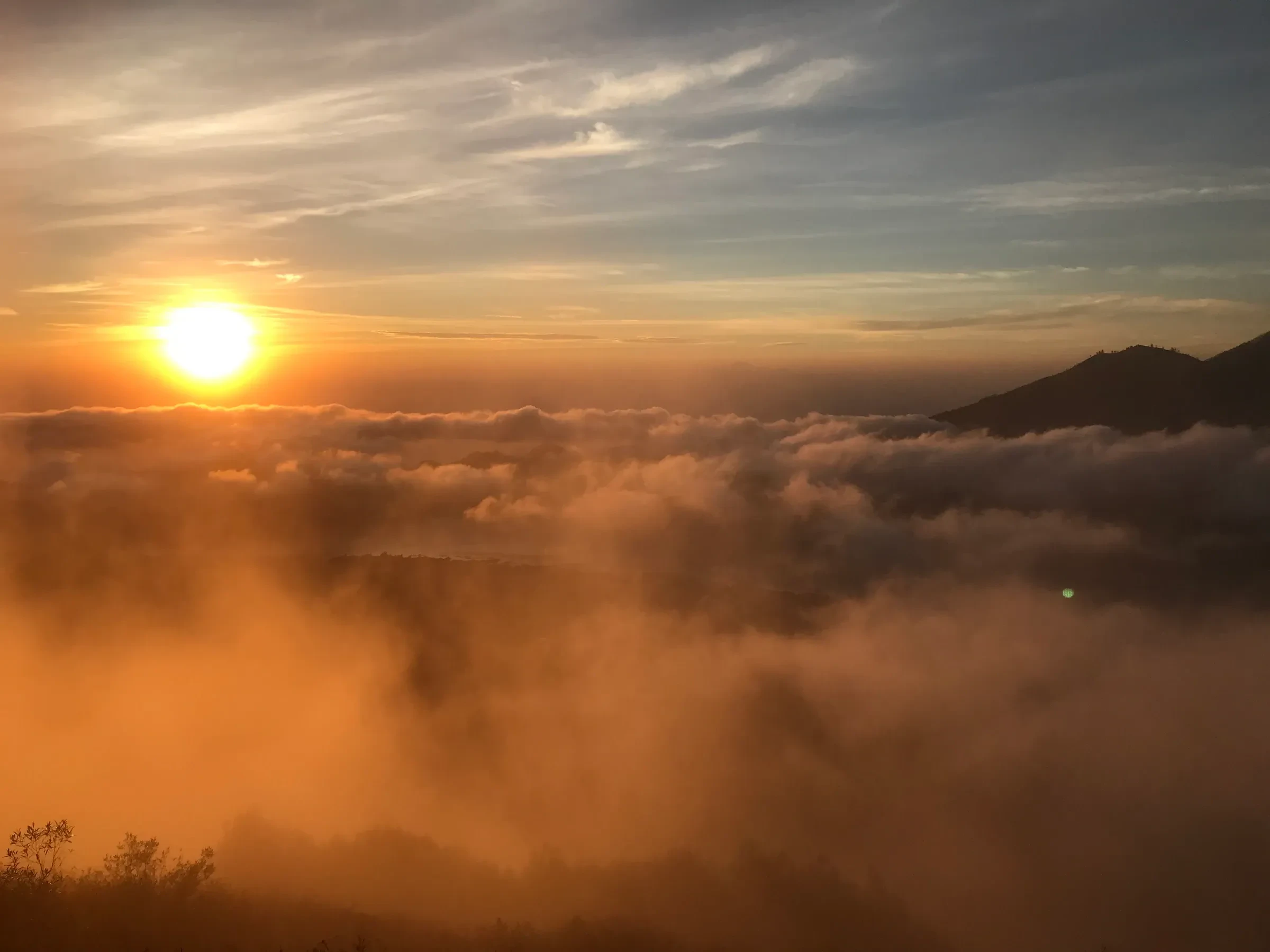 The sun rising above a sea of cloud, seen from Mount Batur