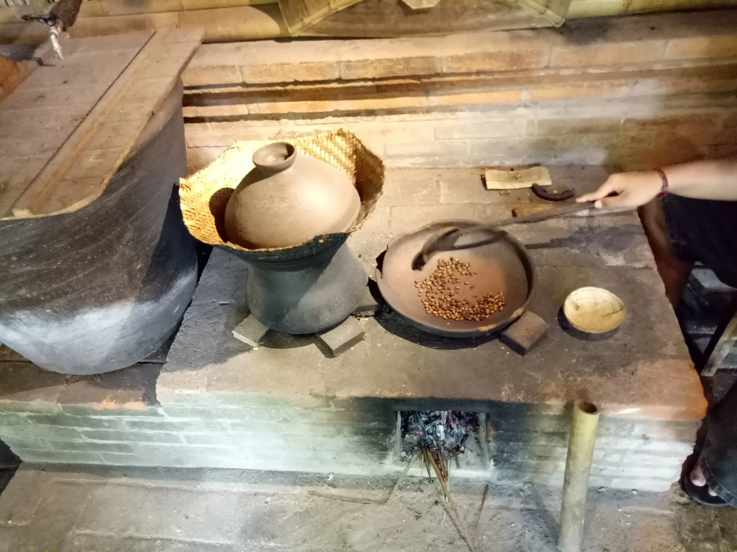 Coffee beans roasting in a clay pan over a wood fire at a coffee plantation in Bali
