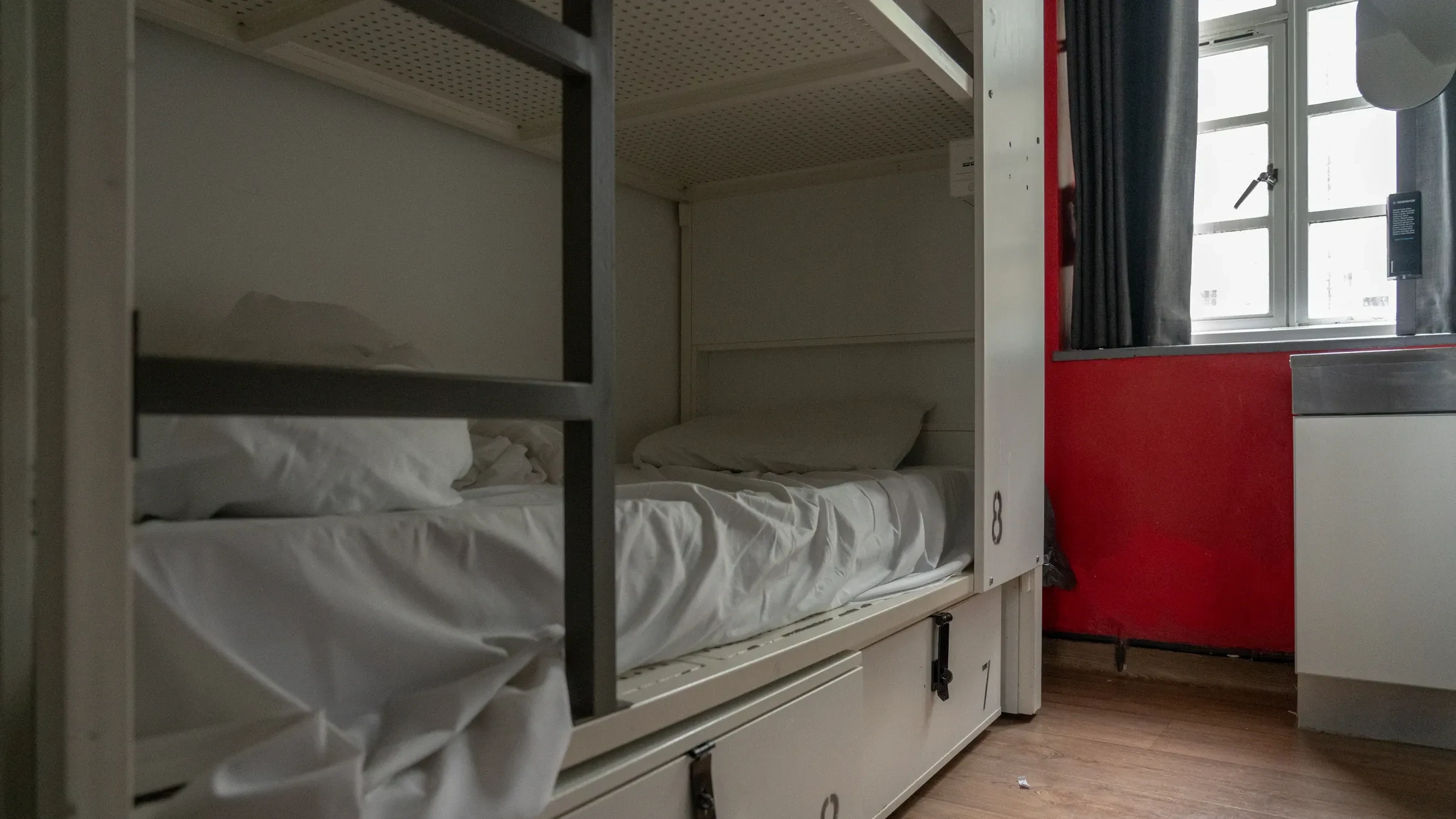 A made bed with white linen in a hostel dormitory
