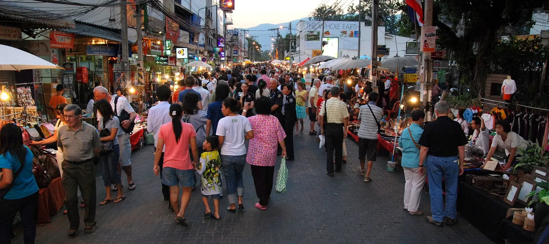 Visitors and stalls along the Sunday Walking Street market on Ratchadamnoen Road in Chiang Mai's Old City at dusk