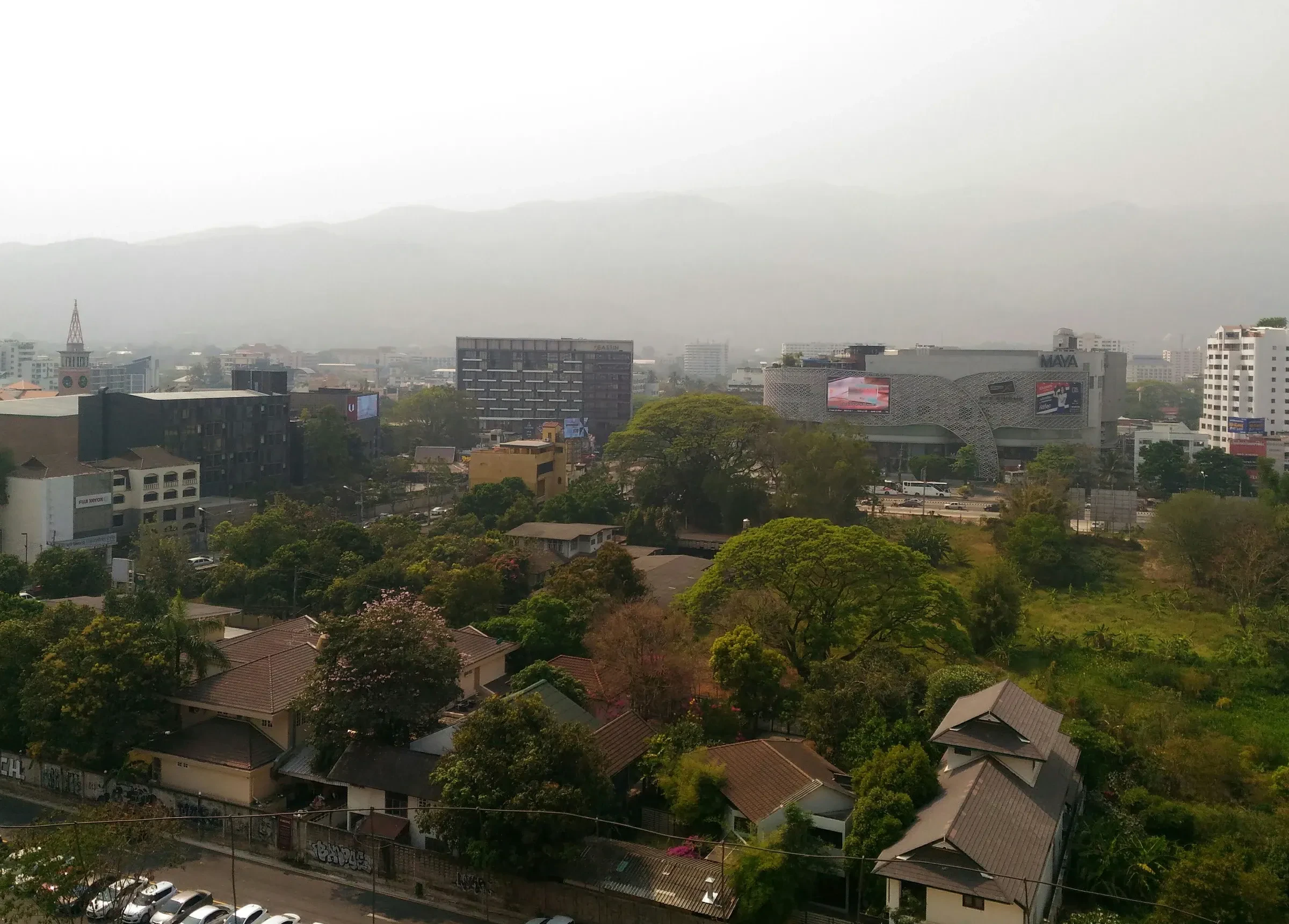 Chiang Mai's rooftops and the hills behind them blurred by grey haze from burning season smoke.
