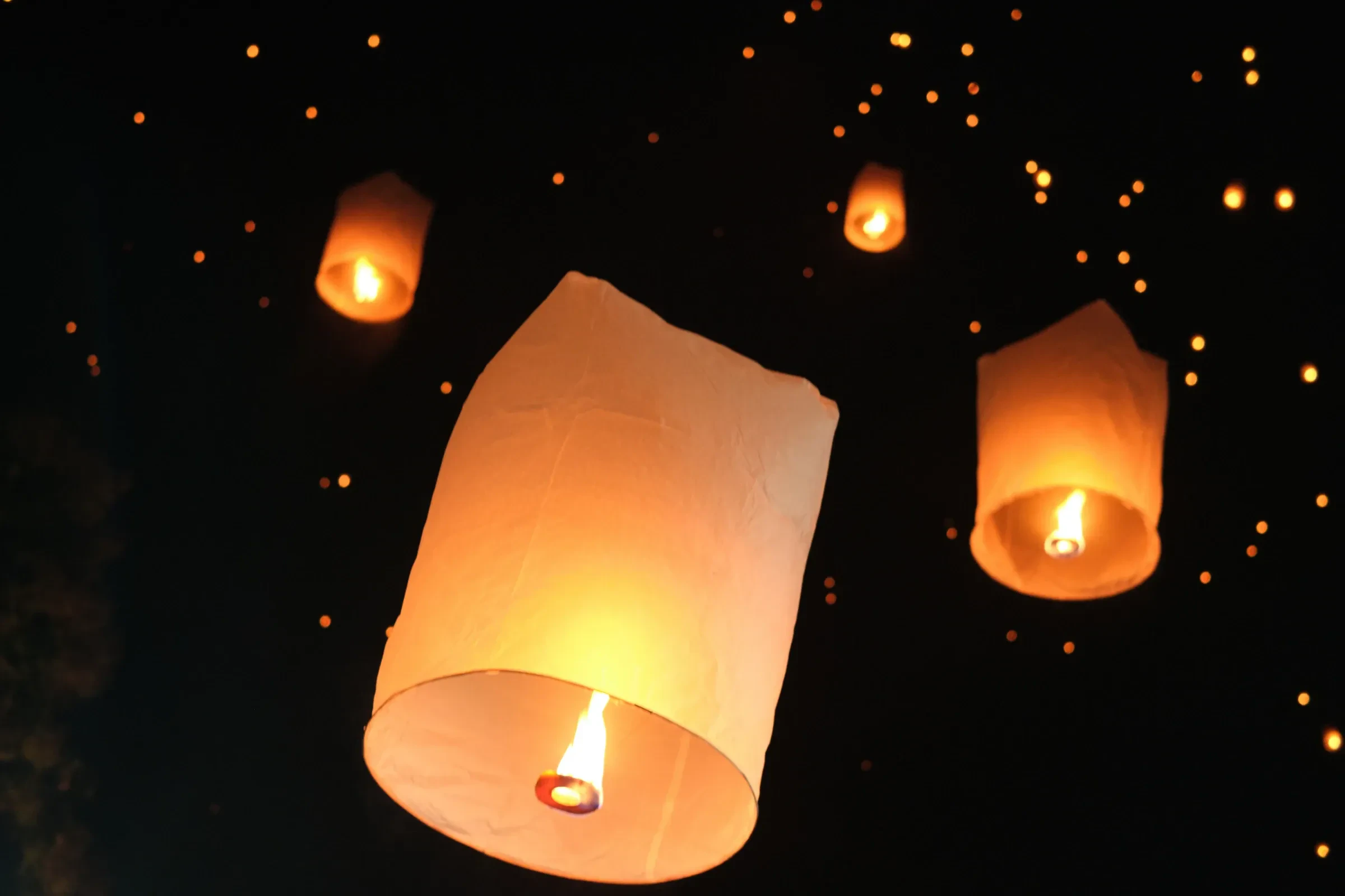 Glowing paper lanterns drifting in the night sky during the festival of lights in Chiang Mai.
