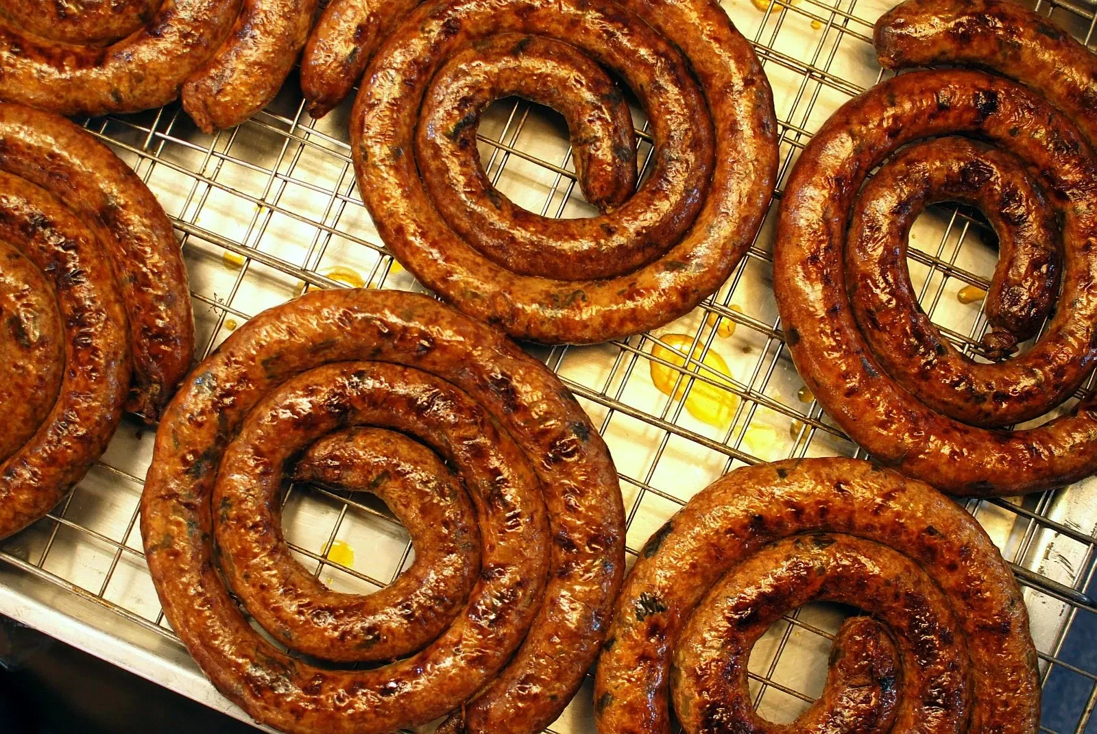 Coils of grilled sai ua sausage on a rack at a Chiang Mai market