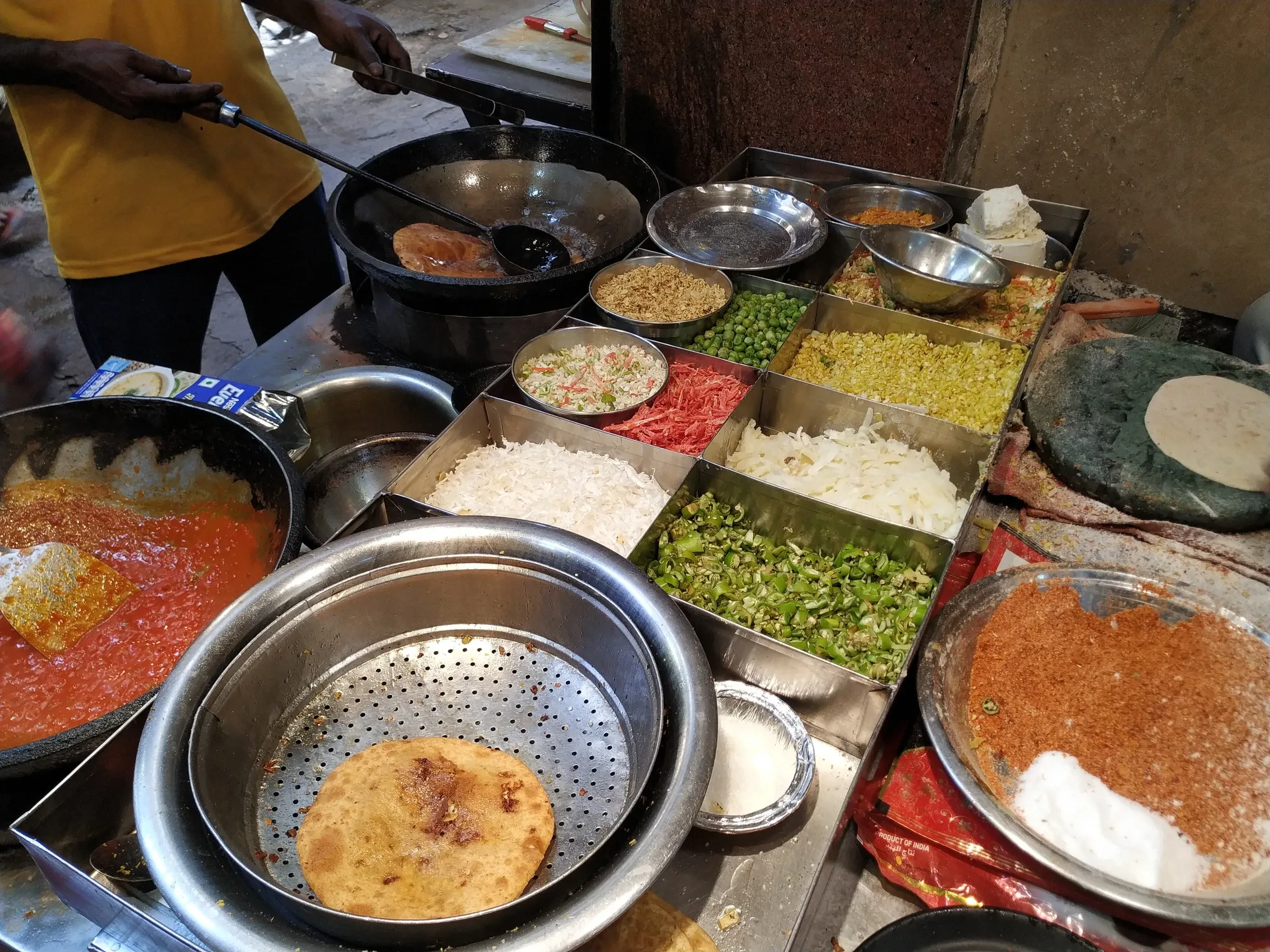 A stall frying paranthe beside trays of fillings in Paranthe Wali Gali, Chandni Chowk