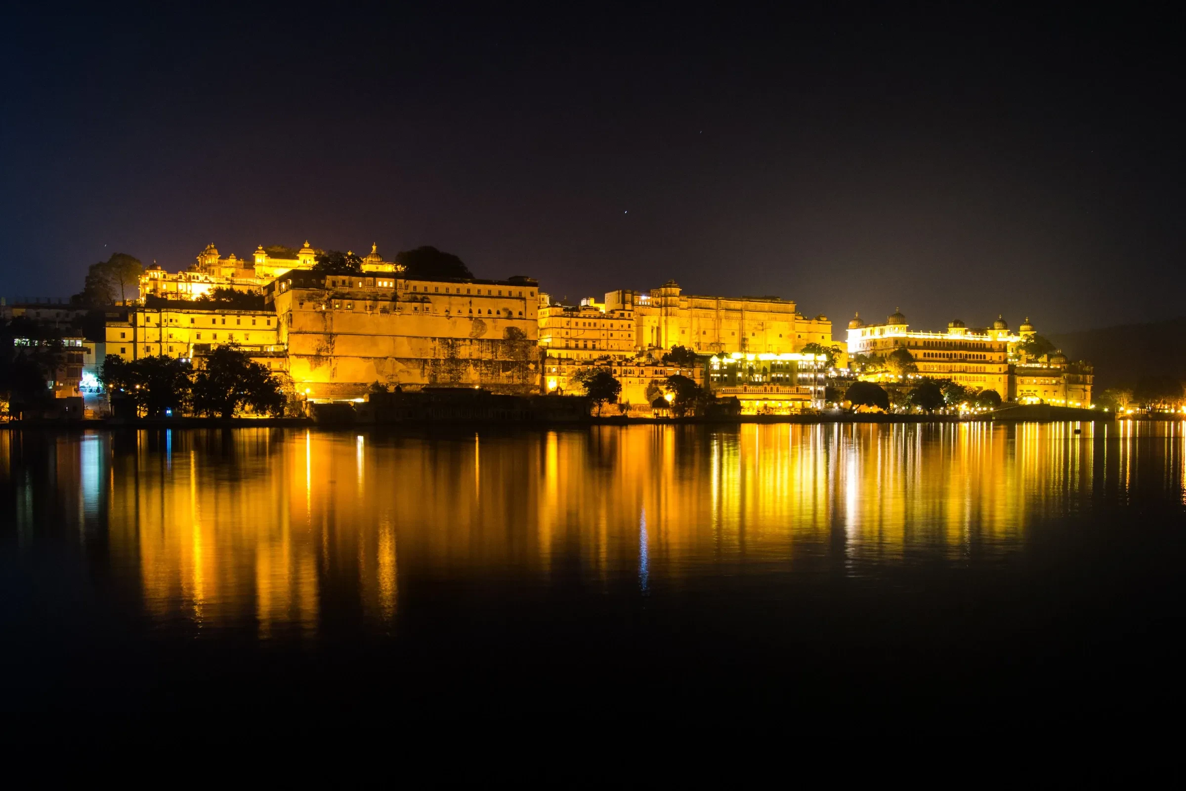 Udaipur's City Palace lit up at night and reflected in Lake Pichola