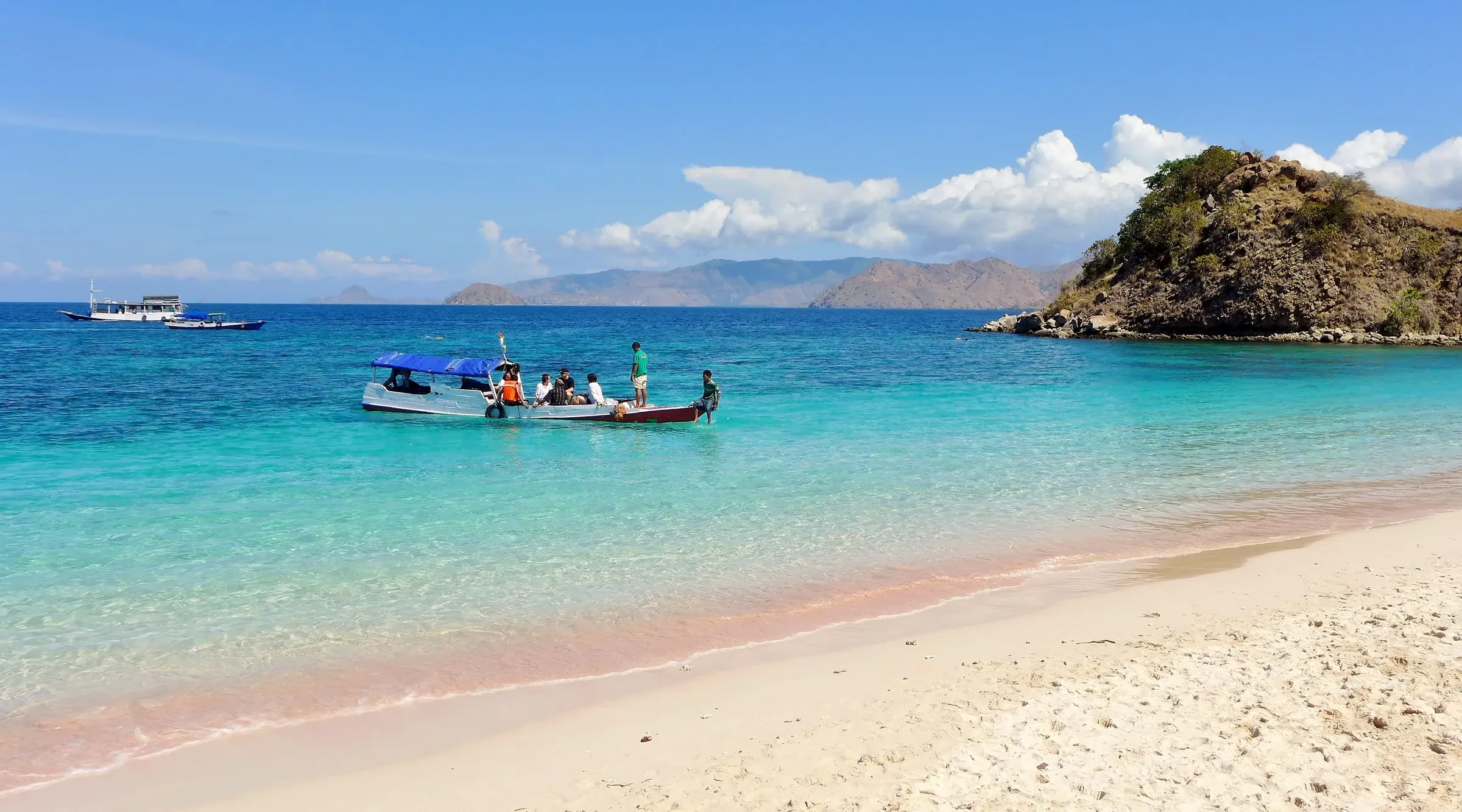 Pink Beach on Komodo, with a boat anchored in turquoise water off the pale pink sand