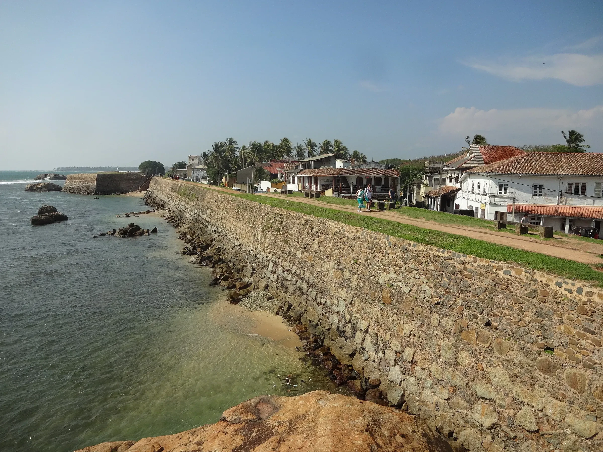 The old Galle Fort sea wall running along the shore, with red roofs of the fort behind