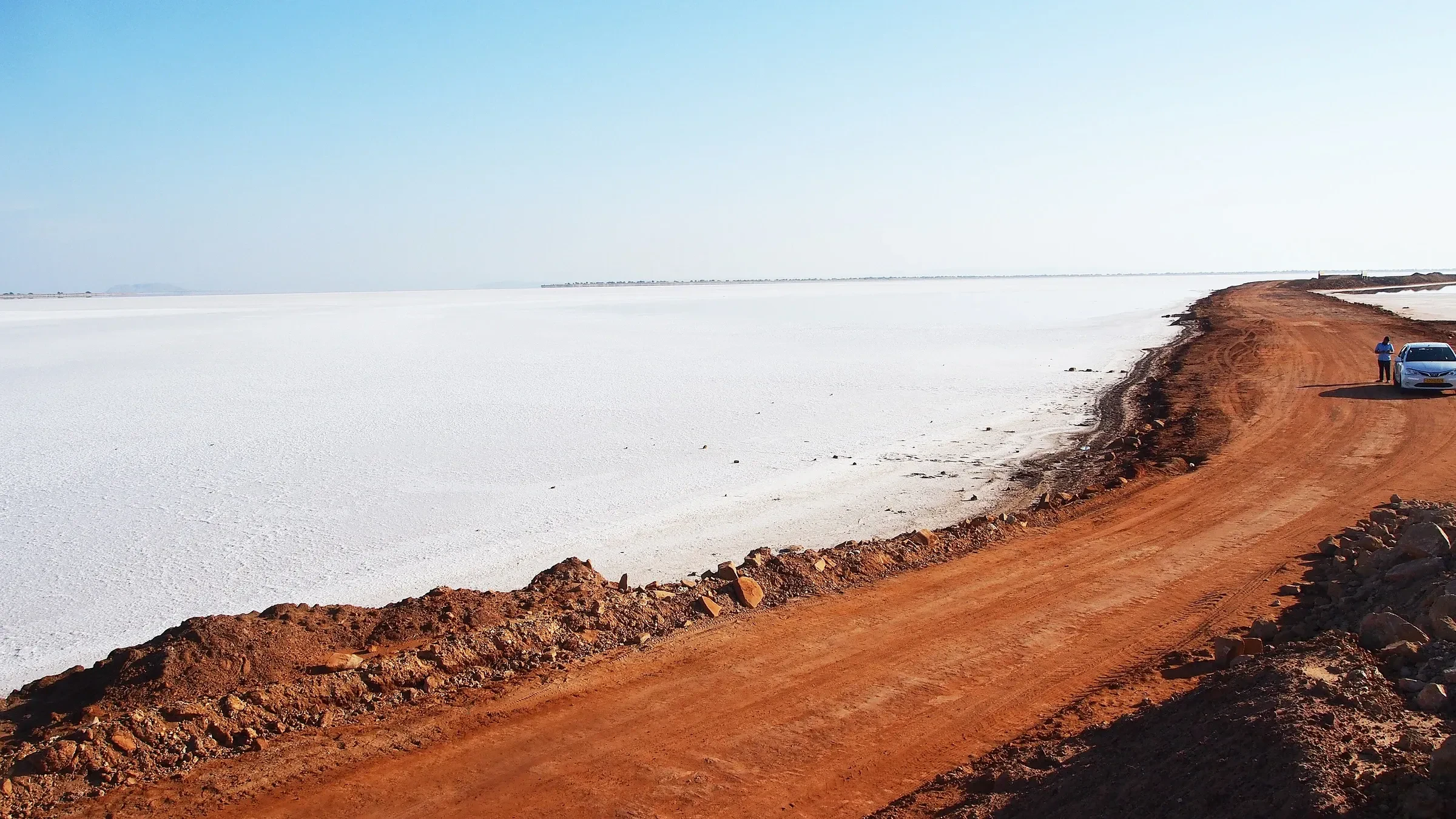 A red earth road beside the white salt desert of the Rann of Kutch
