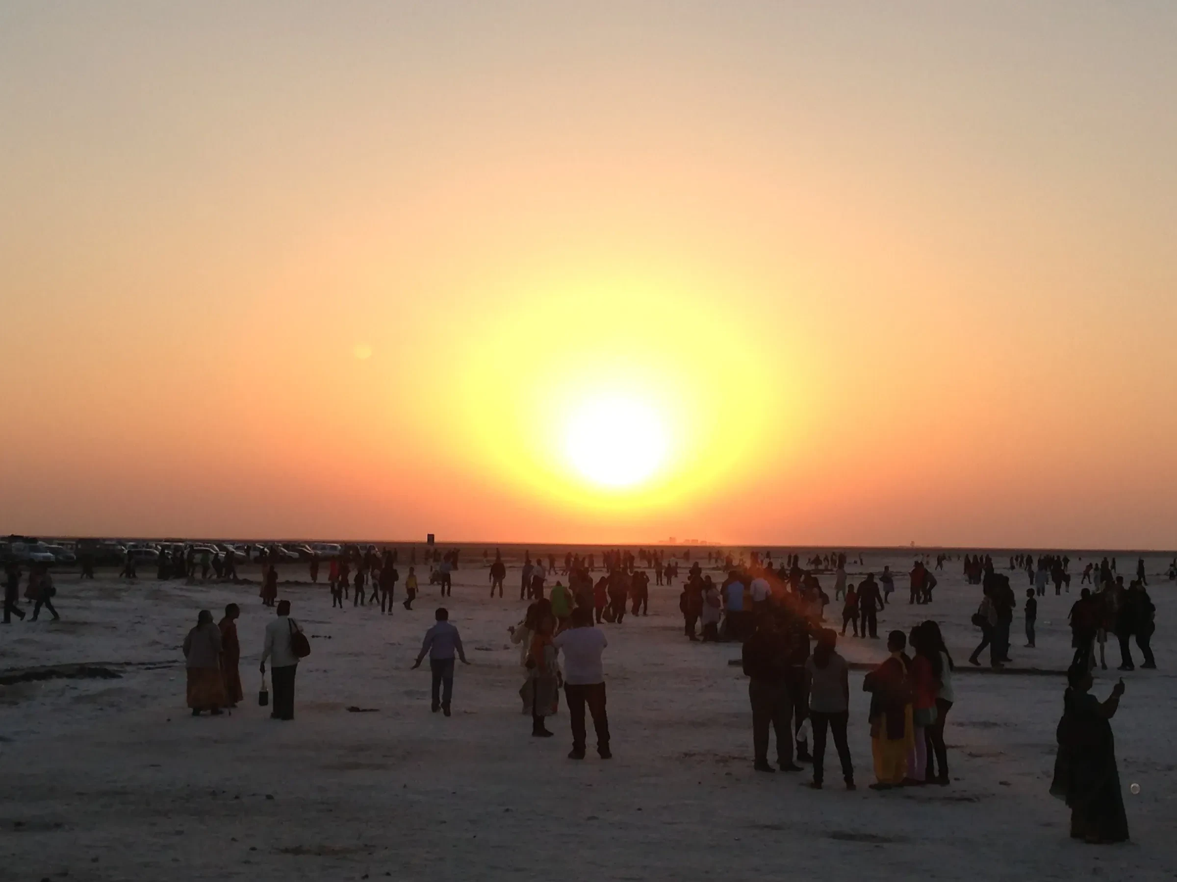 Sunset over the salt flats of the Rann of Kutch, with visitors walking on the crust