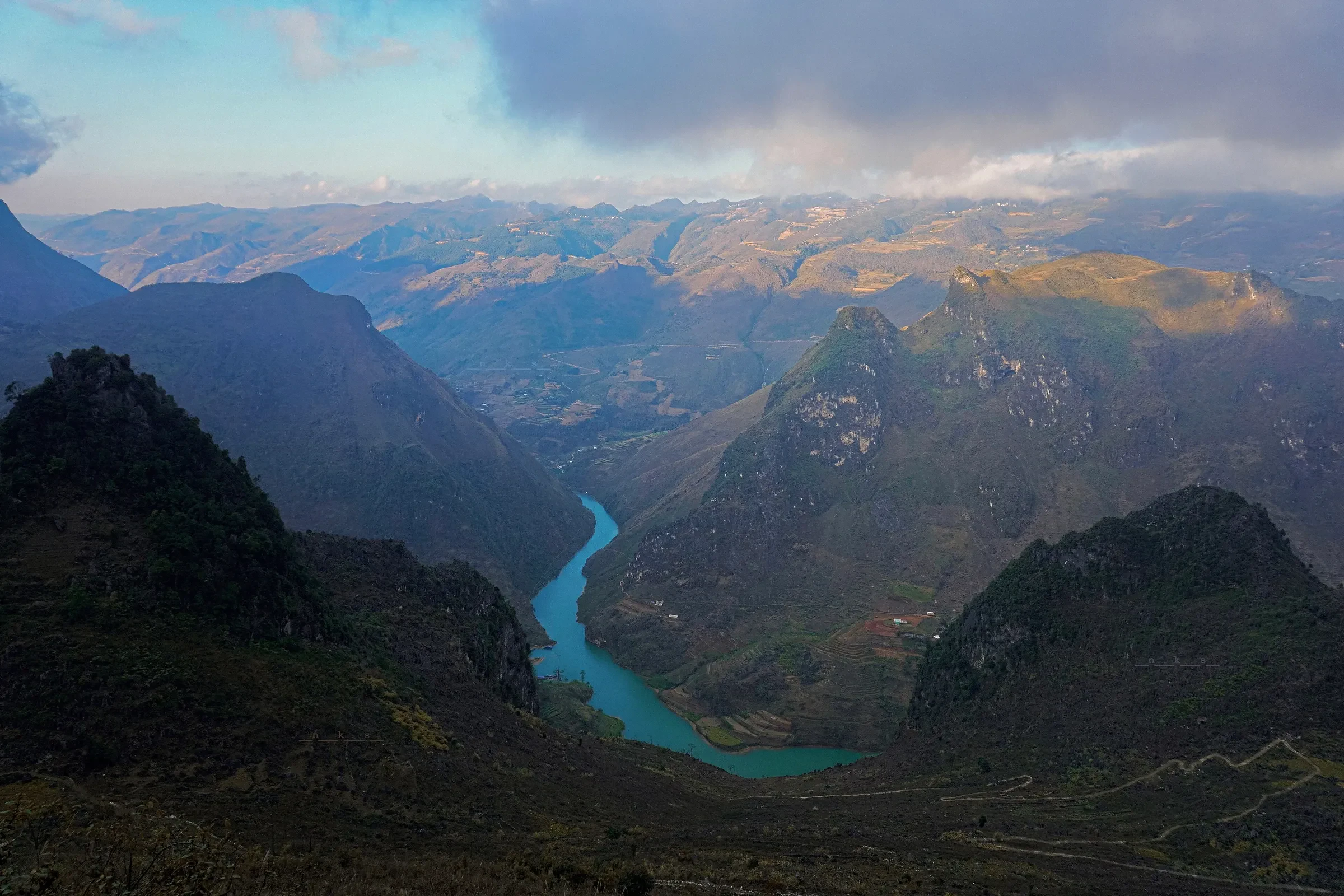 The green Nho Que River winding through a deep canyon below Ma Pi Leng Pass in Ha Giang.