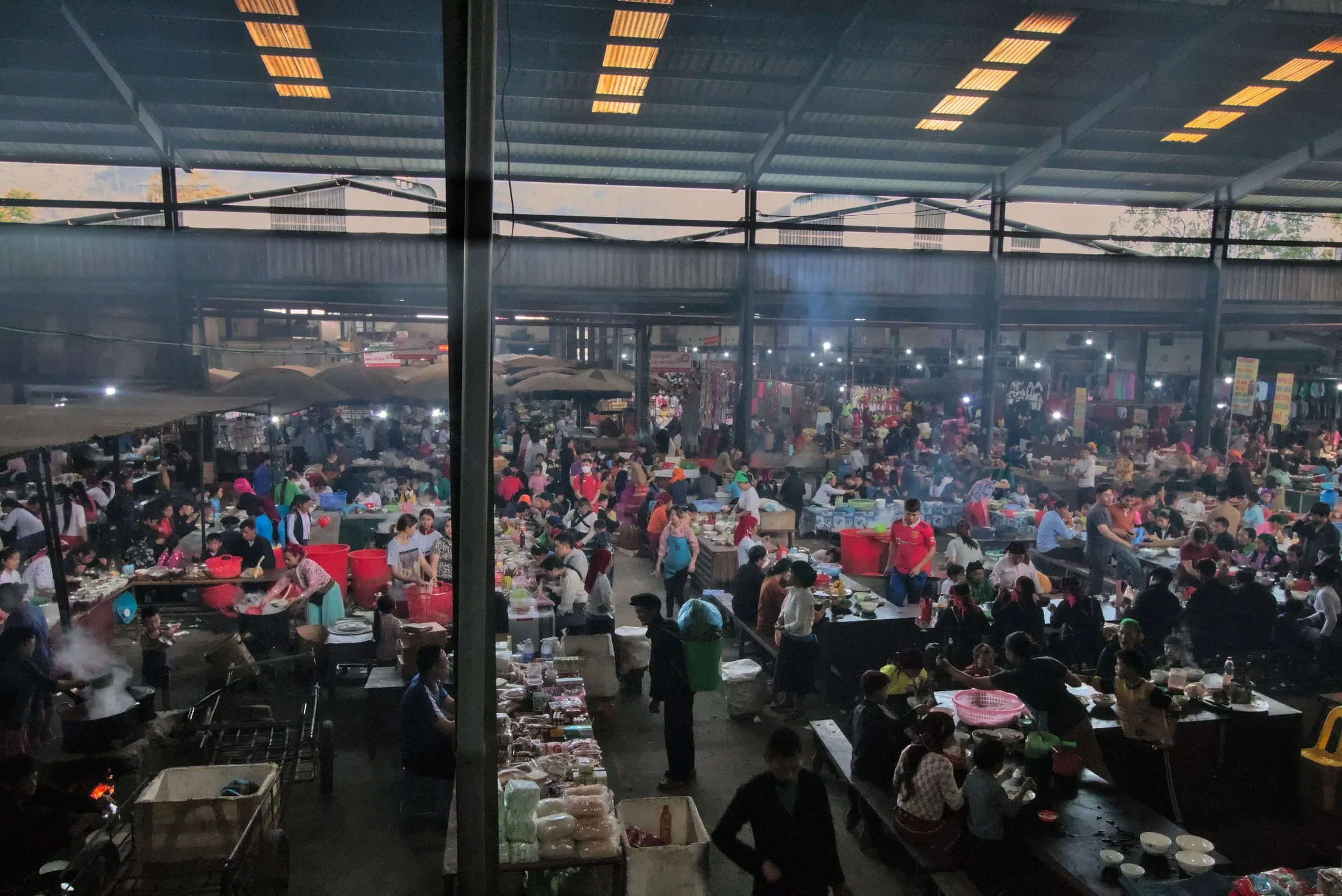 Crowds shopping and eating in the covered market hall in Meo Vac.