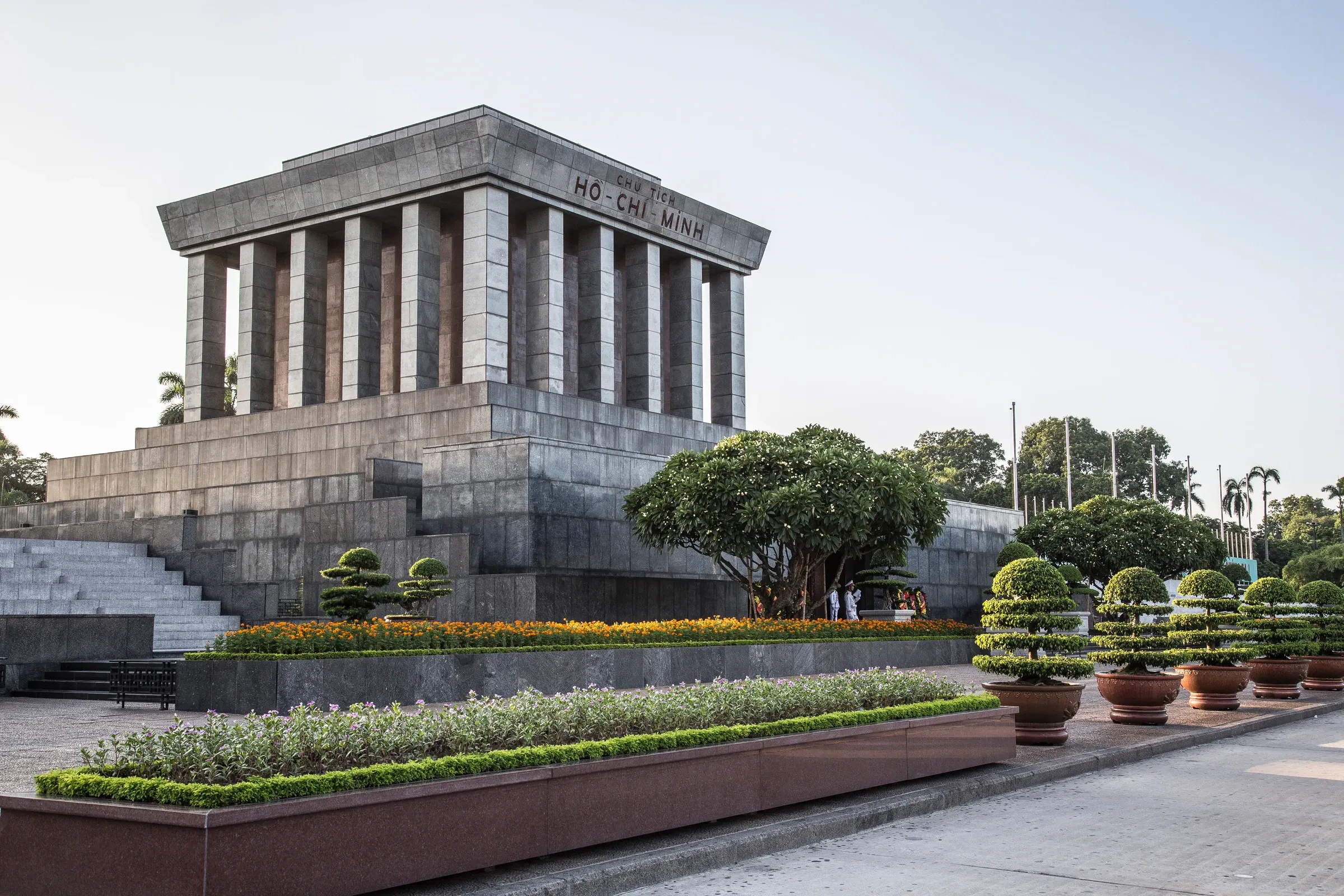 The grey stone Ho Chi Minh Mausoleum in Hanoi, with clipped hedges and flanking gardens