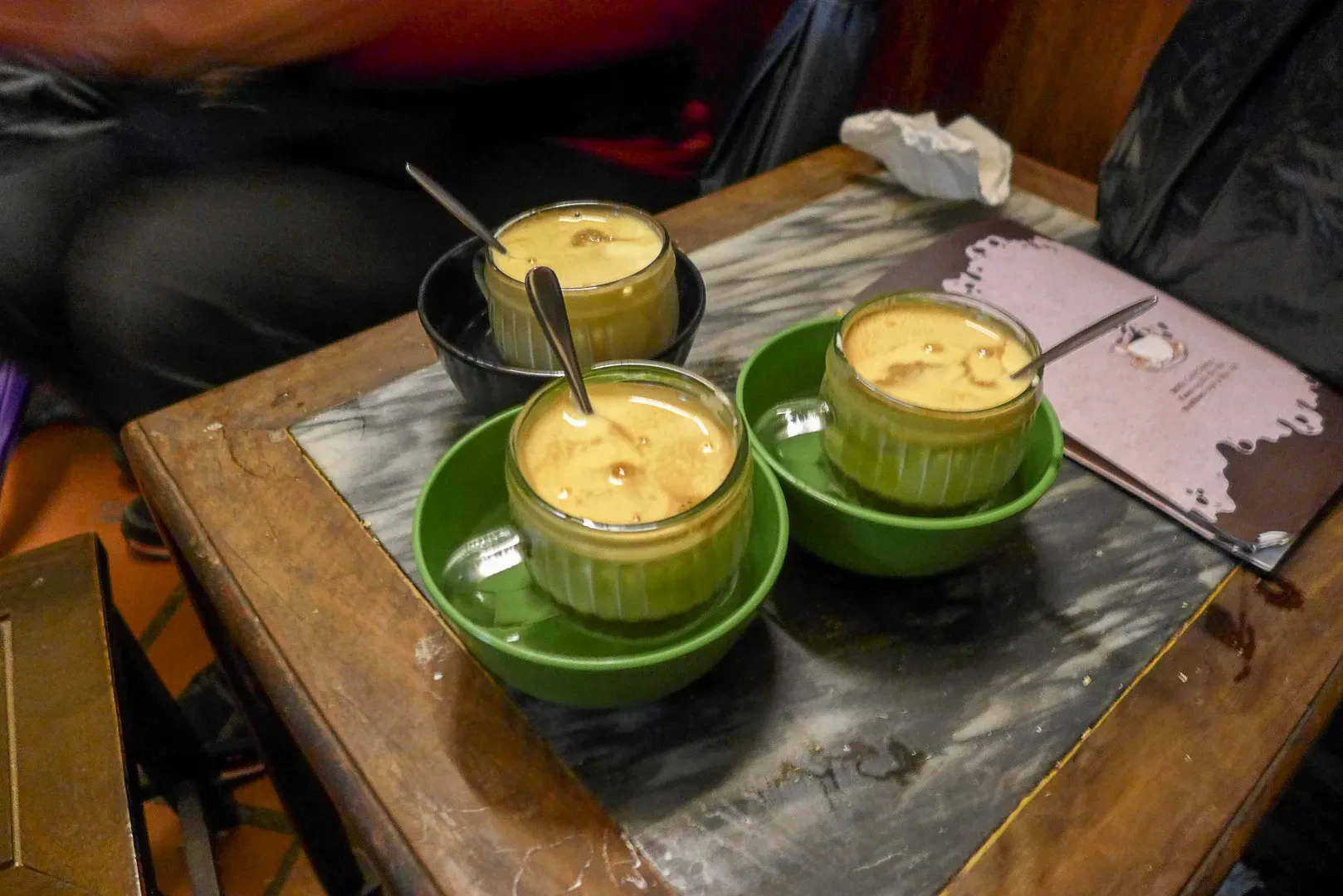 Three cups of egg coffee on a wooden tray at a Hanoi cafe
