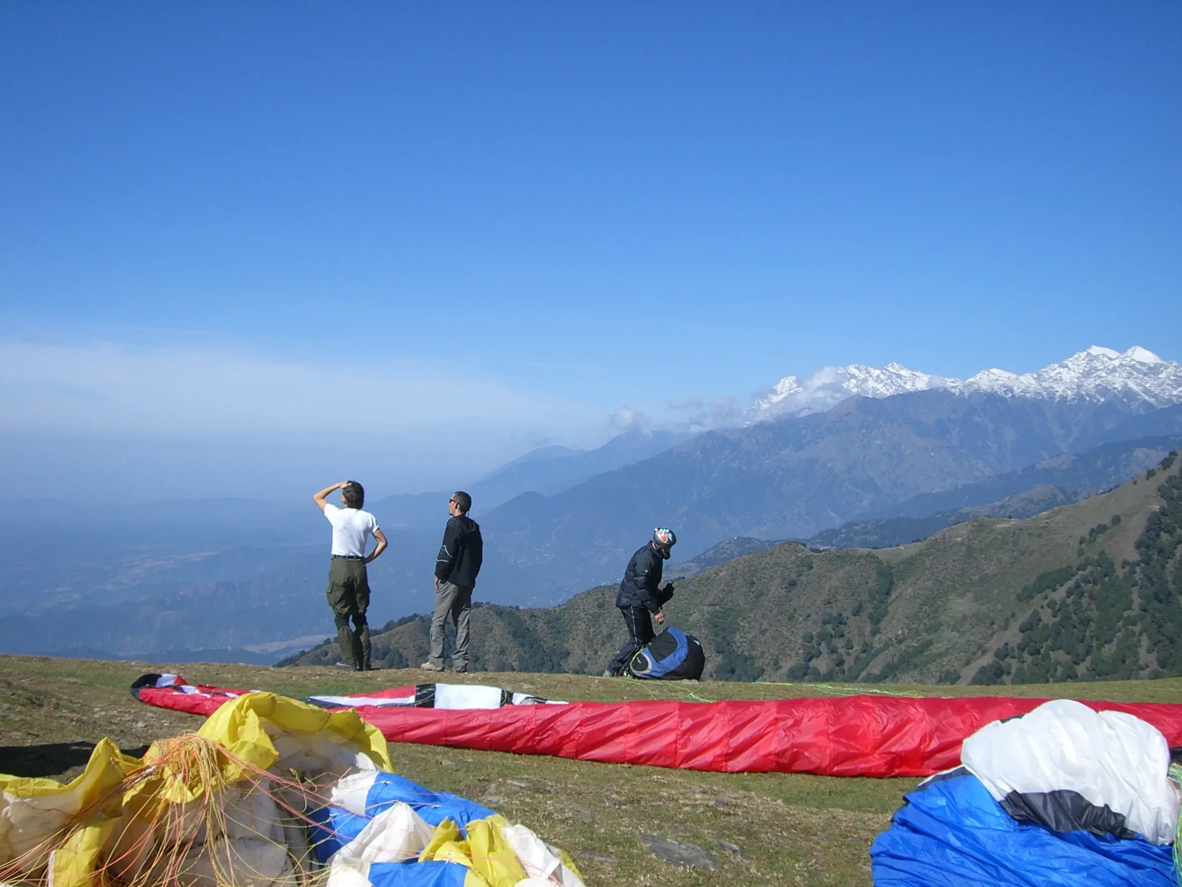 Pilots laying out their wings at the Billing takeoff, with snow peaks beyond