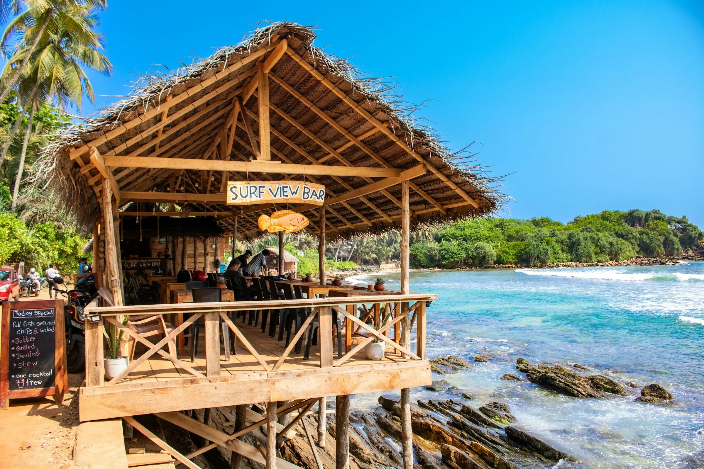The thatched Surf View Bar on the rocks above Hiriketiya beach, with turquoise water beyond