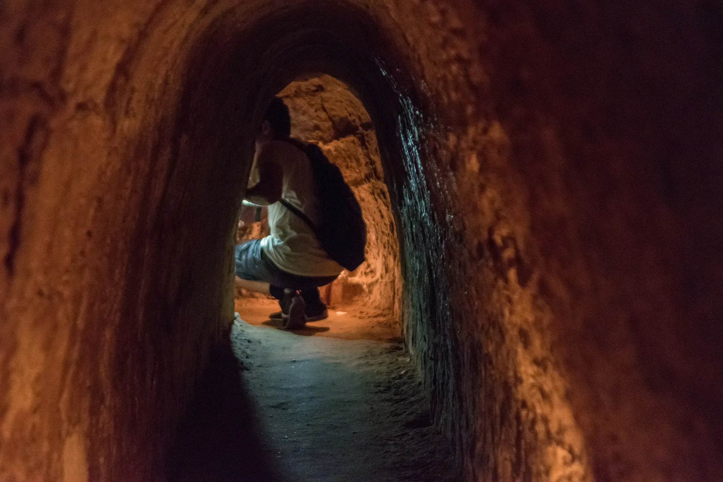 A visitor crouching inside a narrow Cu Chi tunnel passage near Ho Chi Minh City