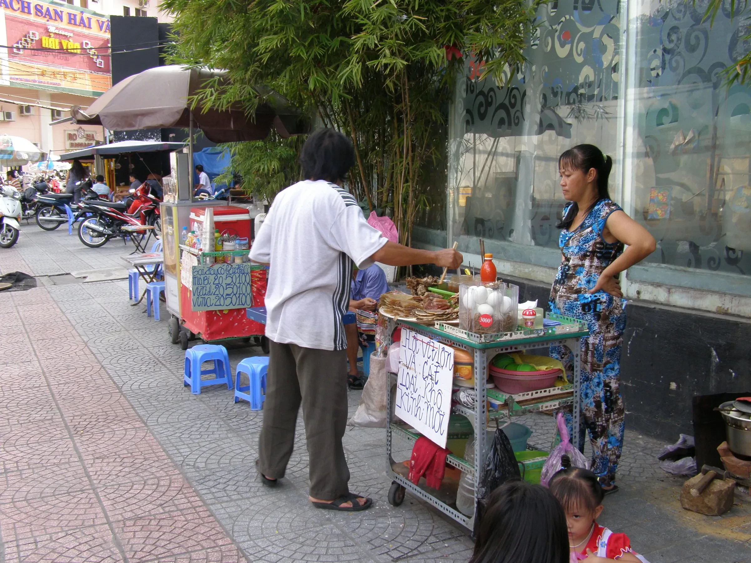 A street food cart serving customers on a pavement in Ho Chi Minh City