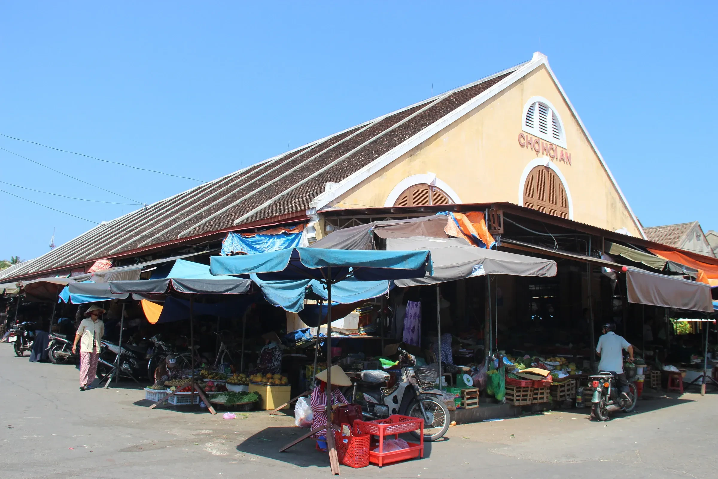 Produce stalls outside the yellow Hoi An Central Market building