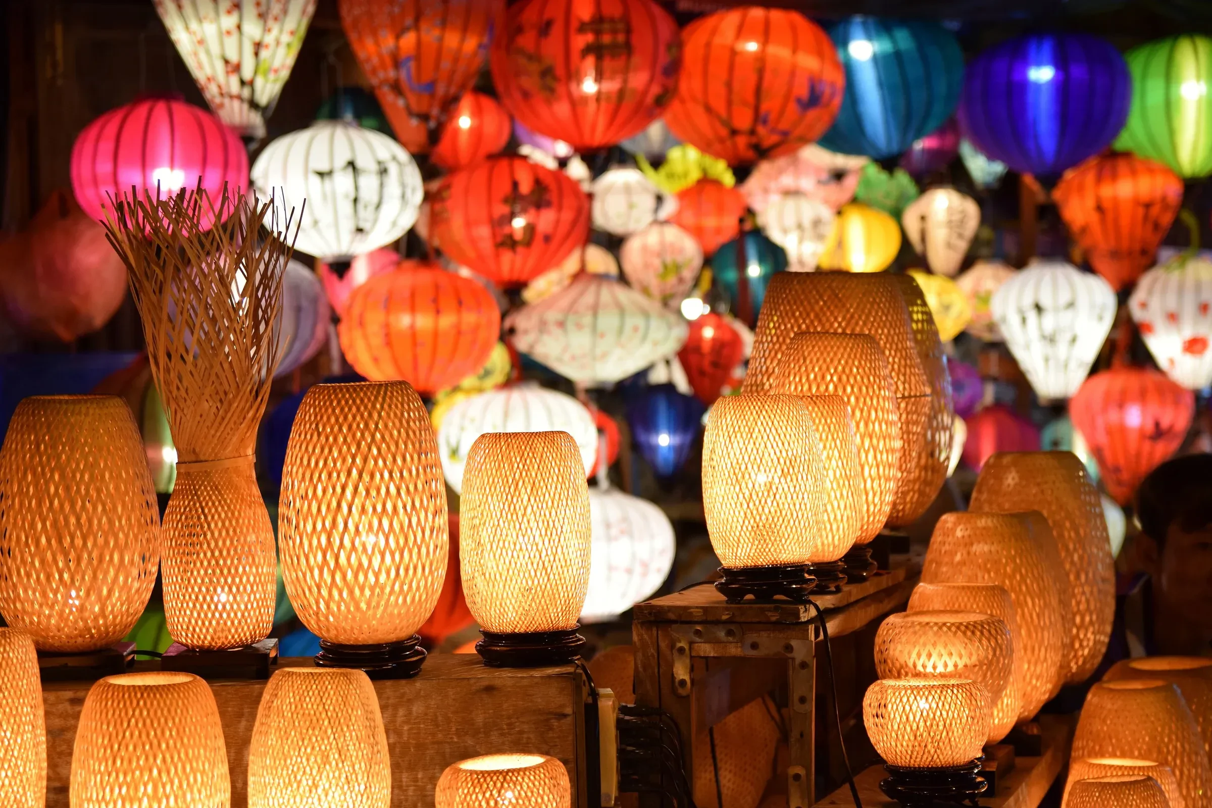 Visitors browsing a stall of silk lanterns in Hoi An's old town at night