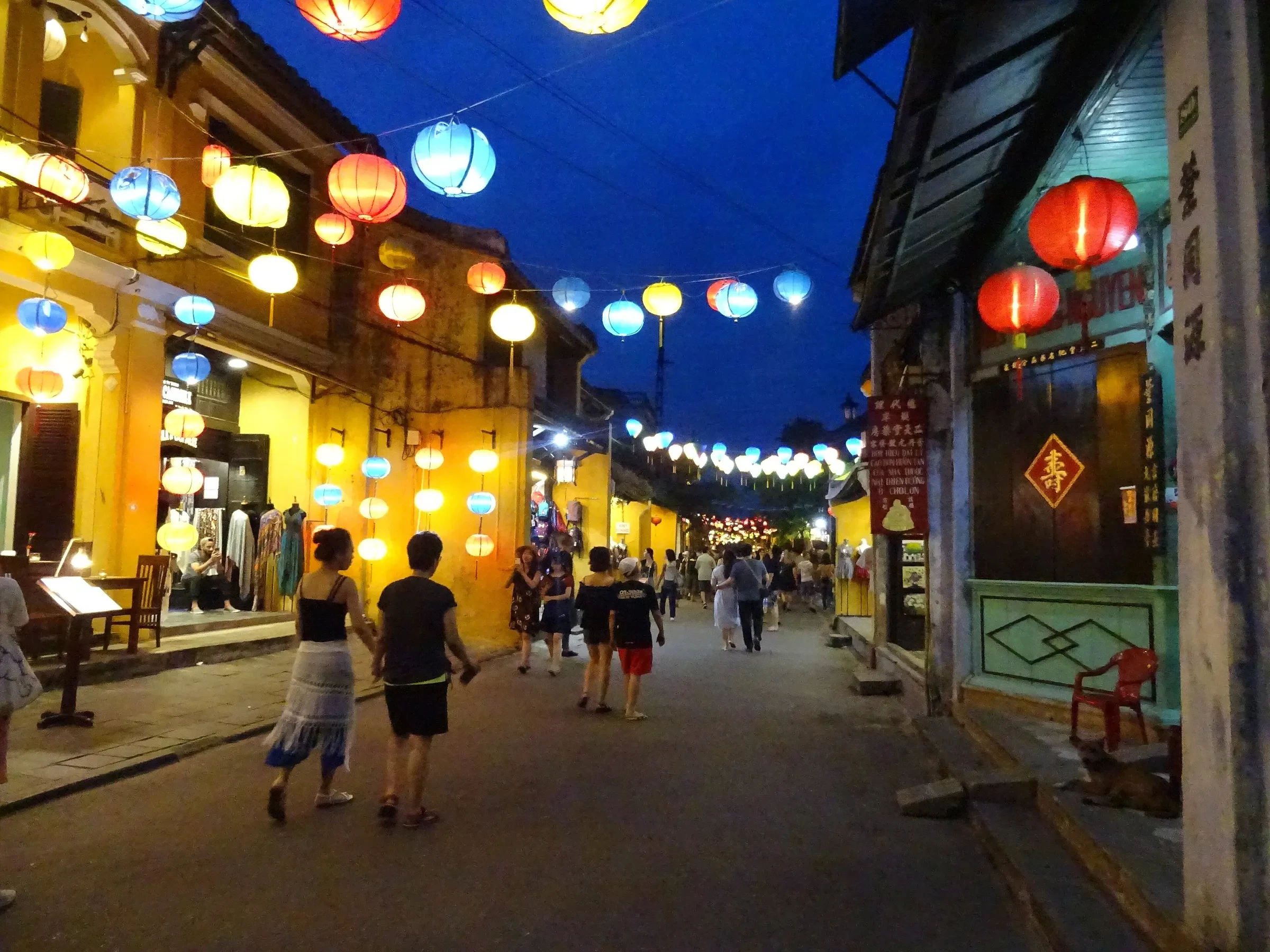 Riverside houses and their lights reflected in the water at night in Hoi An