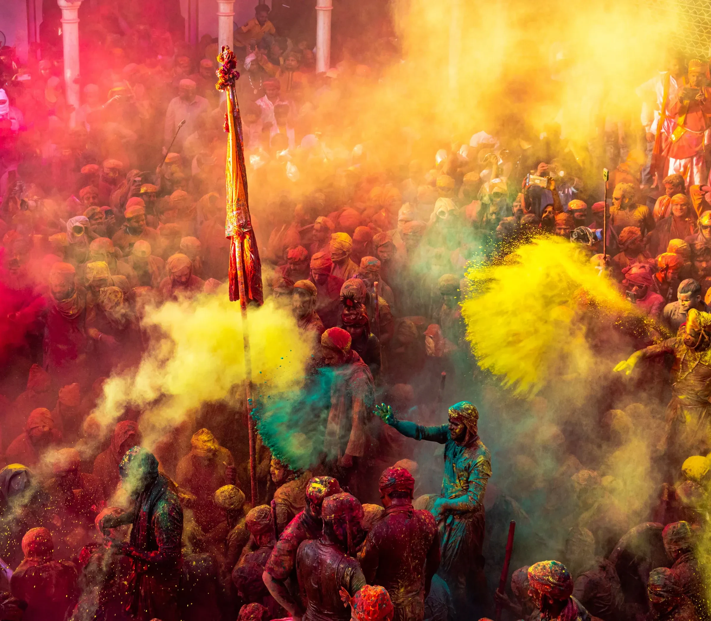 Clouds of yellow and pink powder over the crowd at Lathmar Holi in Nandgaon, Braj