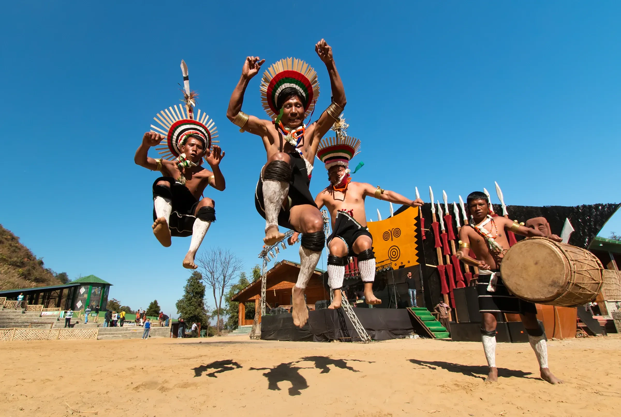 Zeliang Naga dancers in feathered headdresses leaping during a dance at the Hornbill Festival in Nagaland